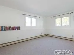 Spare room featuring plenty of natural light, baseboard heating, and carpet floors Spare room featuring plenty of natural light, baseboard heating, and carpet floors