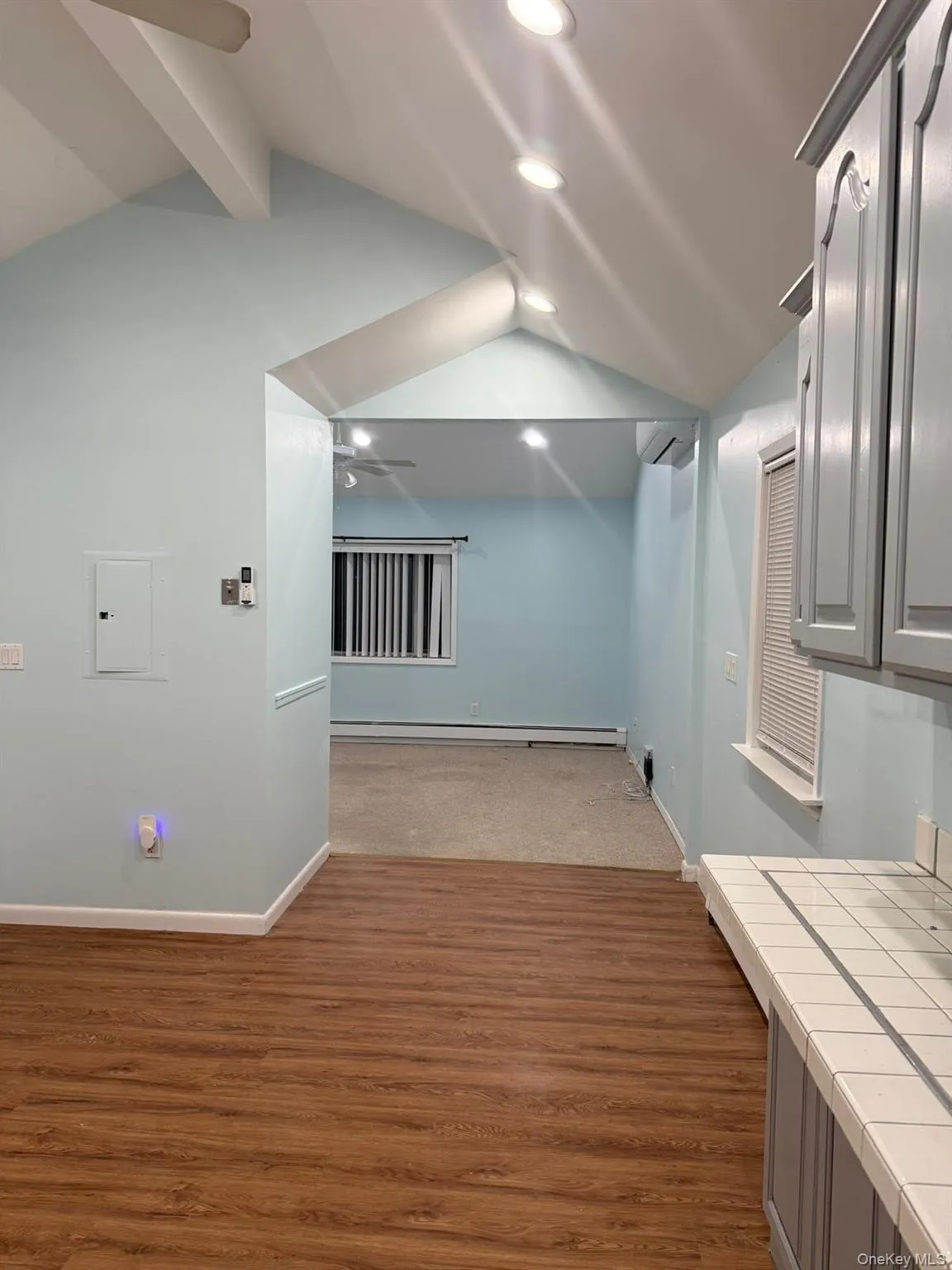 Hall featuring wood finished floors, electric panel, a baseboard heating unit, an AC wall unit, and recessed lighting Hall featuring wood finished floors, electric panel, a baseboard heating unit, an AC wall unit, and recessed lighting