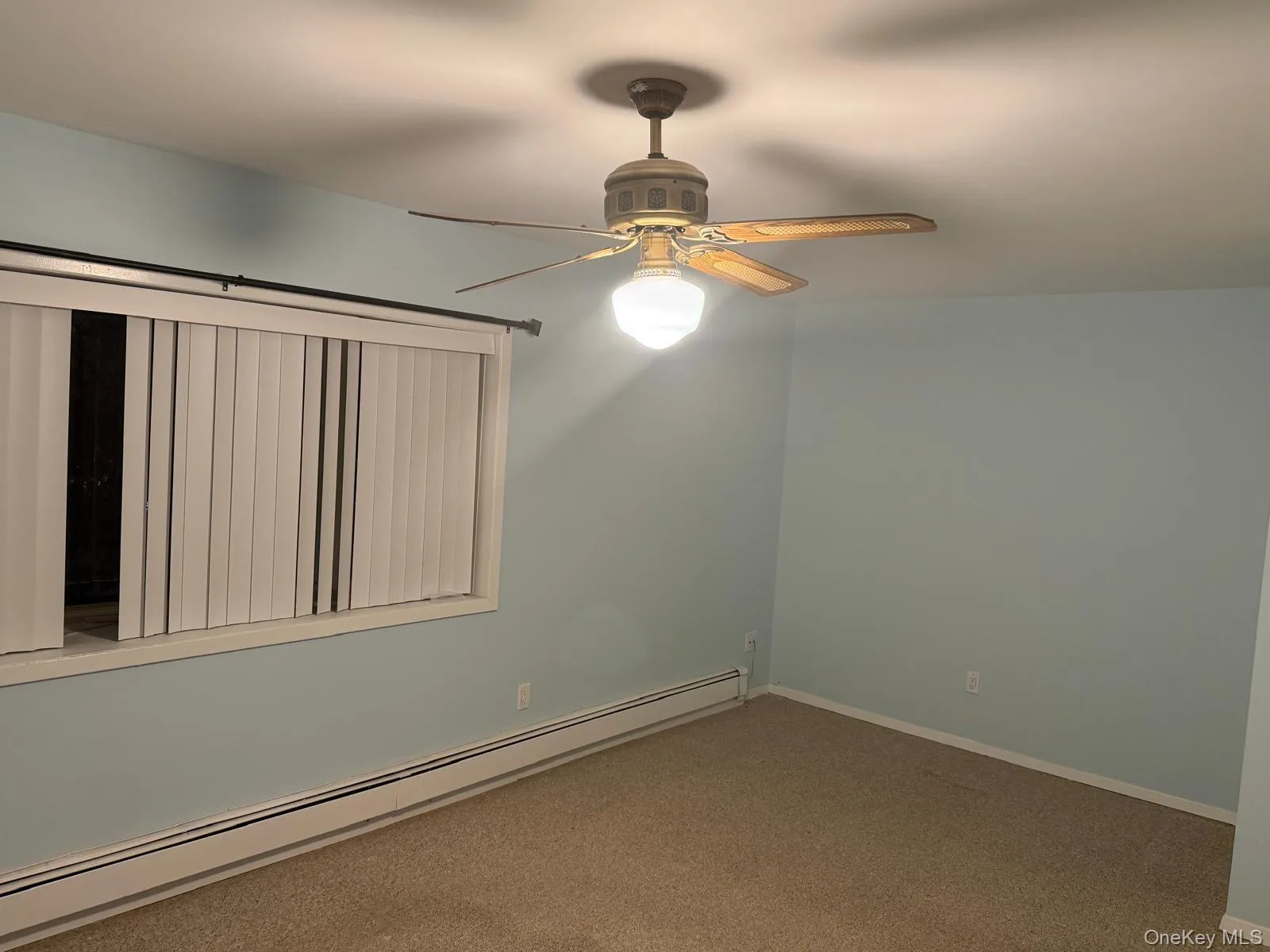 Carpeted empty room featuring a baseboard heating unit and a ceiling fan Carpeted empty room featuring a baseboard heating unit and a ceiling fan