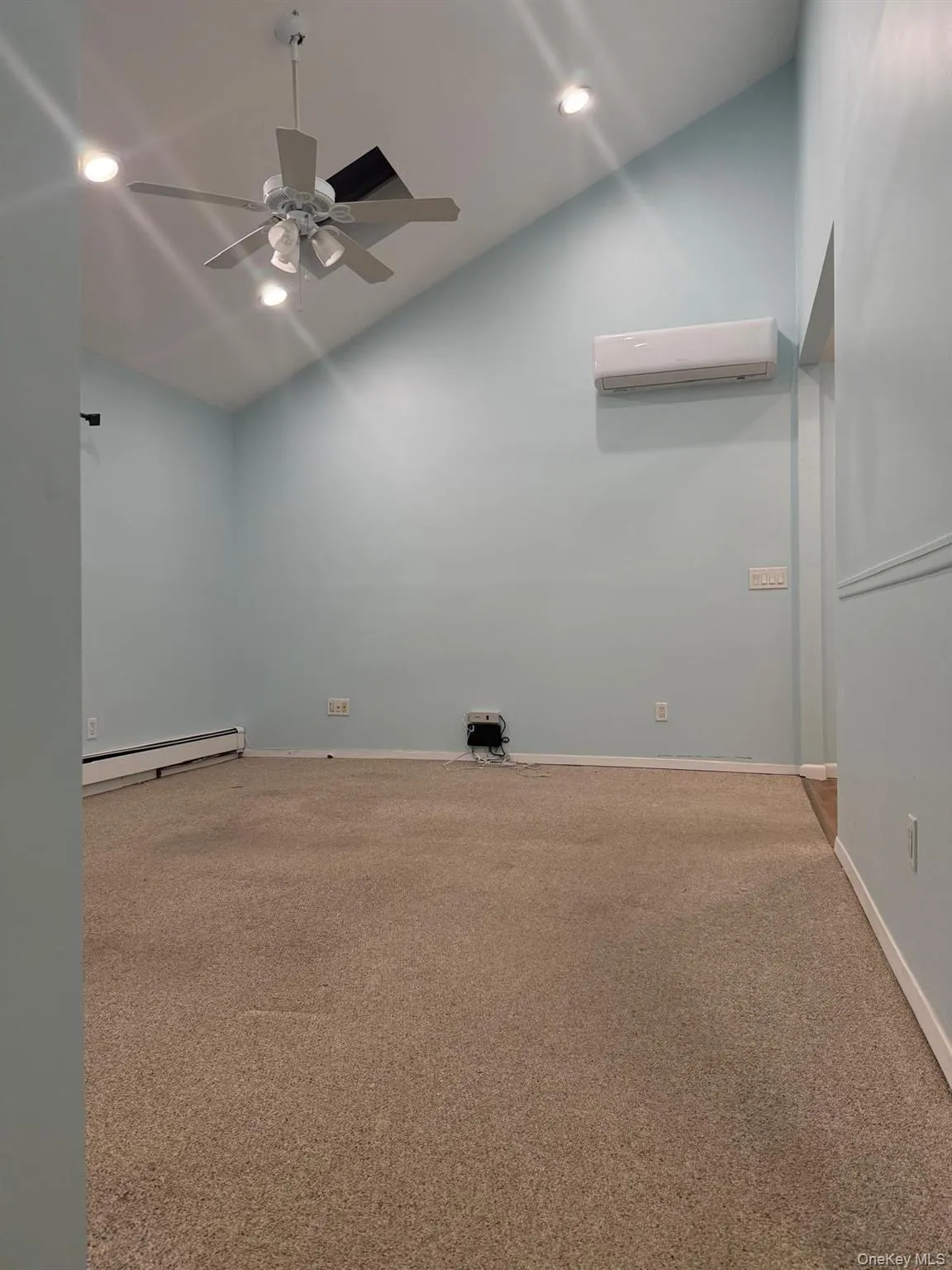 Spare room featuring vaulted ceiling, light colored carpet, recessed lighting, a baseboard radiator, and a ceiling fan Spare room featuring vaulted ceiling, light colored carpet, recessed lighting, a baseboard radiator, and a ceiling fan