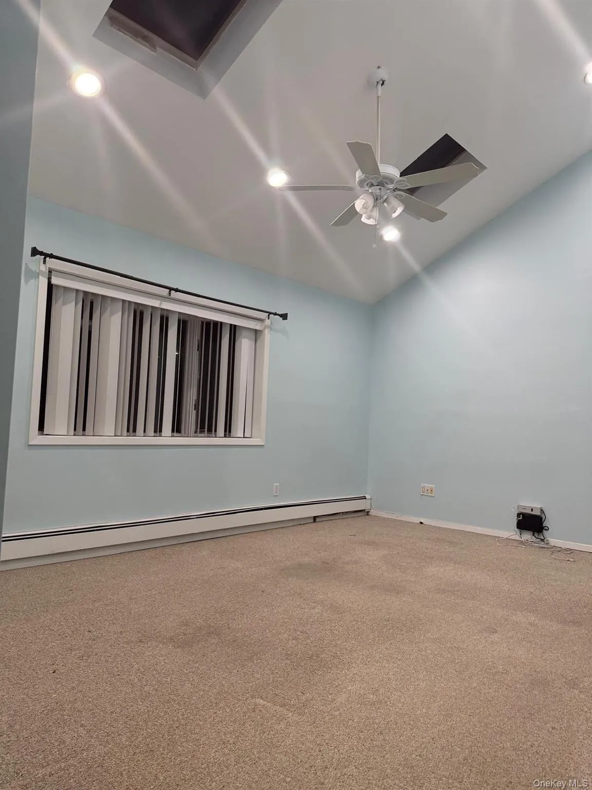 Carpeted empty room featuring baseboard heating, recessed lighting, lofted ceiling, and a ceiling fan Carpeted empty room featuring baseboard heating, recessed lighting, lofted ceiling, and a ceiling fan