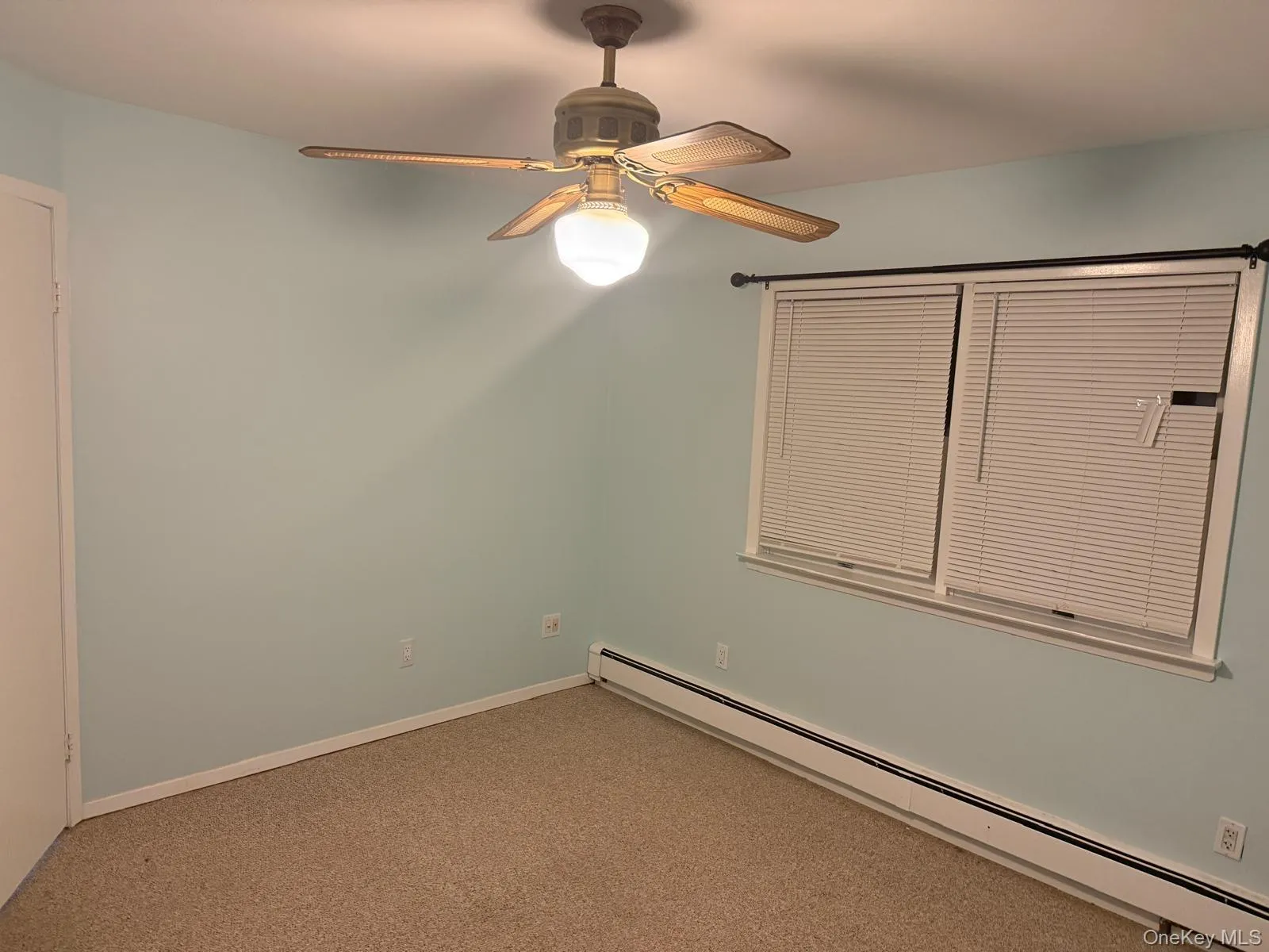 Carpeted spare room with baseboard heating and a ceiling fan Carpeted spare room with baseboard heating and a ceiling fan