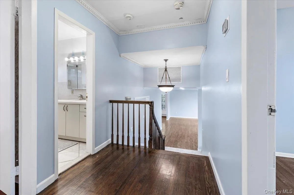 Corridor featuring an upstairs landing, dark wood-style flooring, and ornamental molding Corridor featuring an upstairs landing, dark wood-style flooring, and ornamental molding