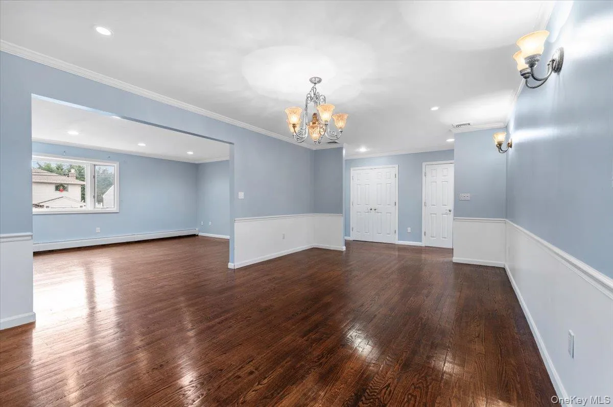 Unfurnished room featuring recessed lighting, dark wood finished floors, a baseboard radiator, crown molding, and a chandelier Unfurnished room featuring recessed lighting, dark wood finished floors, a baseboard radiator, crown molding, and a chandelier