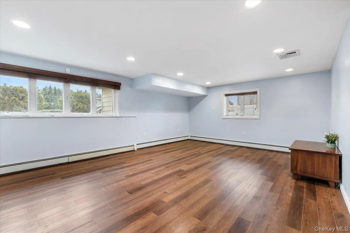 Additional living space with dark wood-type flooring, a baseboard heating unit, and recessed lighting Additional living space with dark wood-type flooring, a baseboard heating unit, and recessed lighting