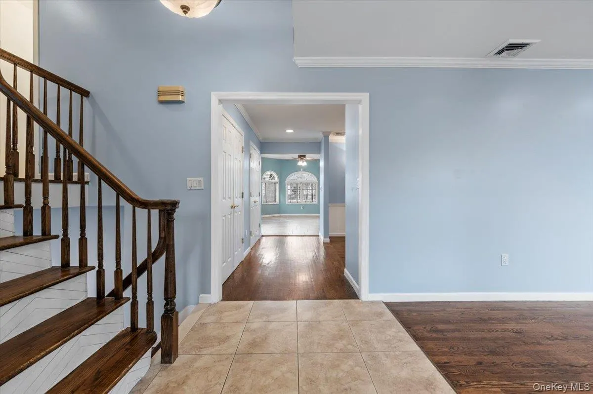 Foyer featuring dark tile patterned floors, stairs, a ceiling fan, and ornamental molding Foyer featuring dark tile patterned floors, stairs, a ceiling fan, and ornamental molding