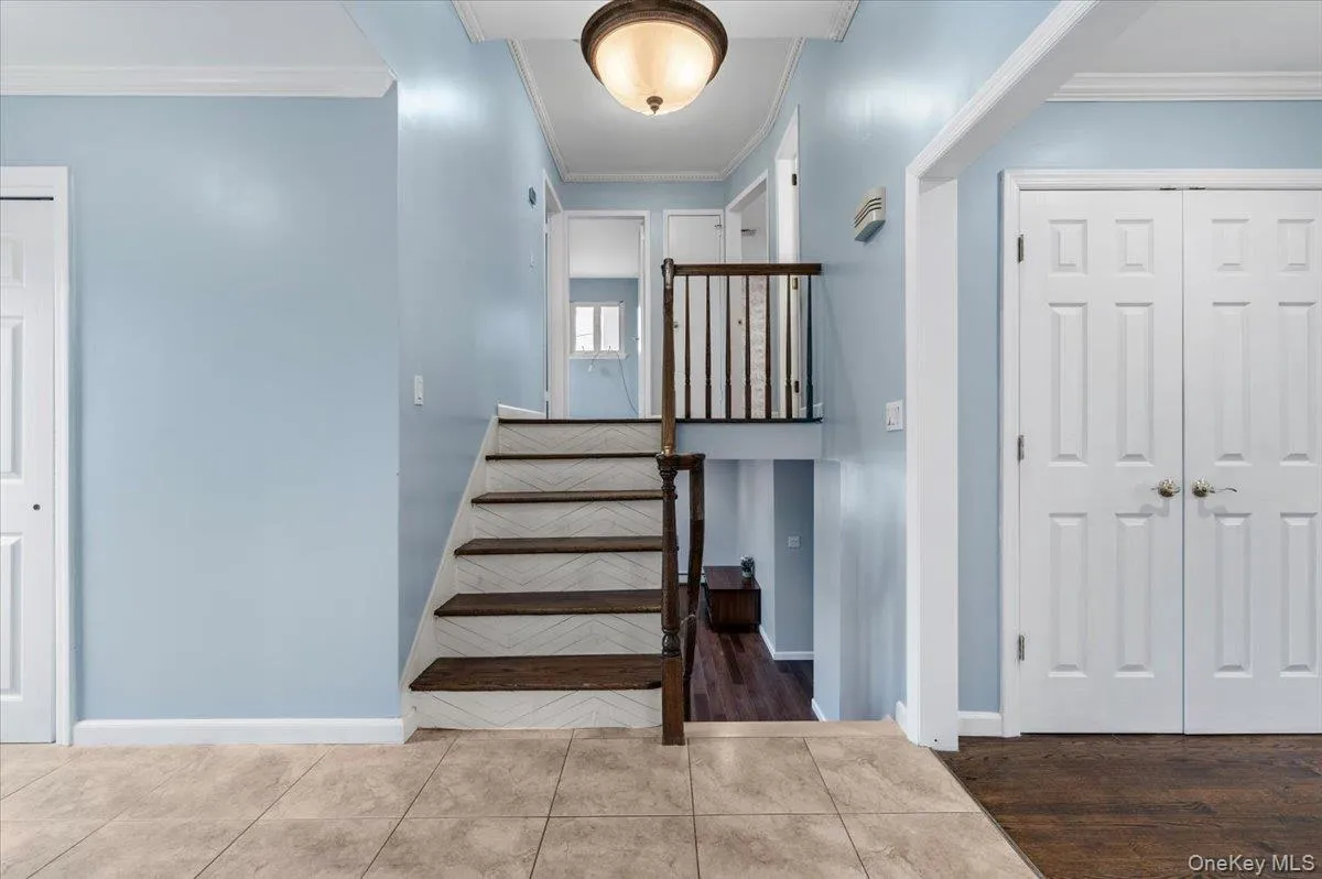 Stairway featuring crown molding and tile patterned flooring Stairway featuring crown molding and tile patterned flooring