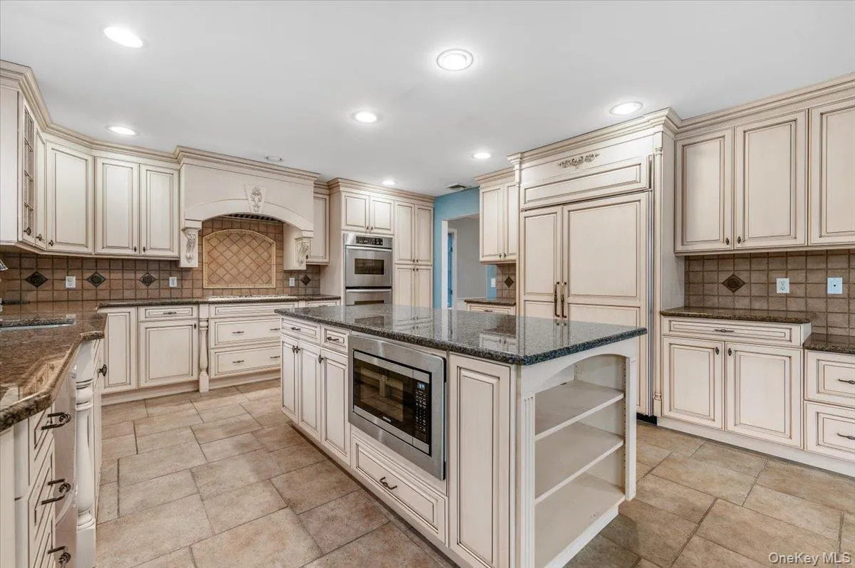 Kitchen featuring cream cabinetry, decorative backsplash, built in appliances, and recessed lighting Kitchen featuring cream cabinetry, decorative backsplash, built in appliances, and recessed lighting