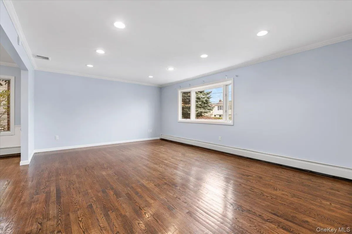 Spare room featuring ornamental molding, baseboard heating, recessed lighting, and dark wood-style flooring Spare room featuring ornamental molding, baseboard heating, recessed lighting, and dark wood-style flooring