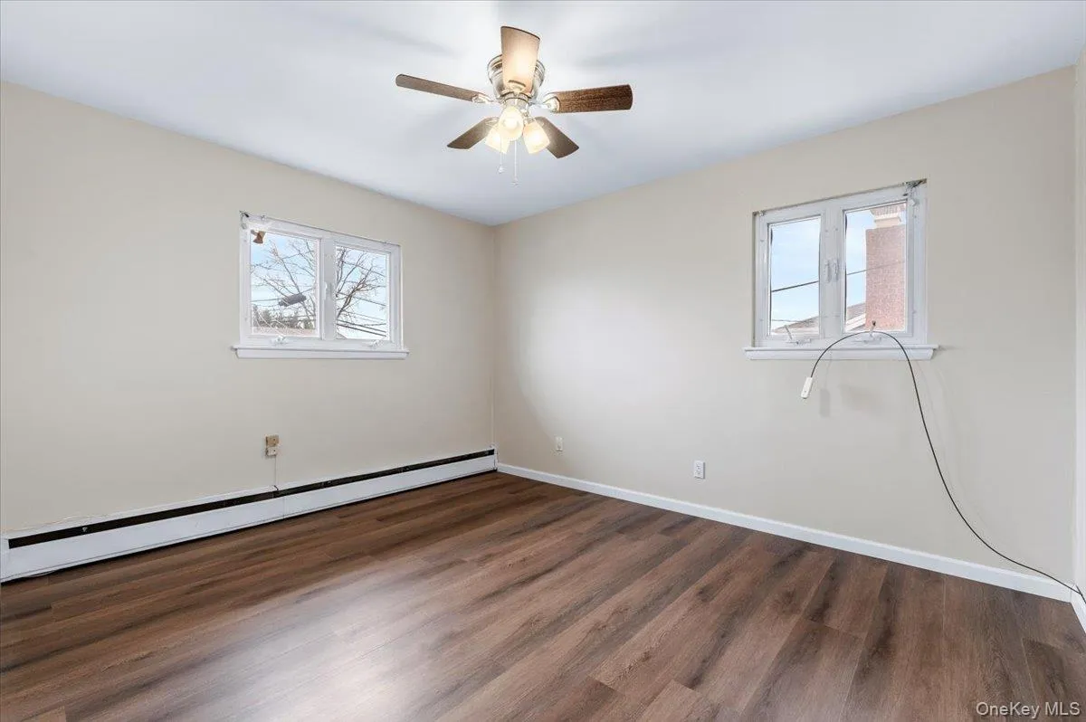Unfurnished room featuring a baseboard radiator, dark wood-style flooring, and a ceiling fan Unfurnished room featuring a baseboard radiator, dark wood-style flooring, and a ceiling fan
