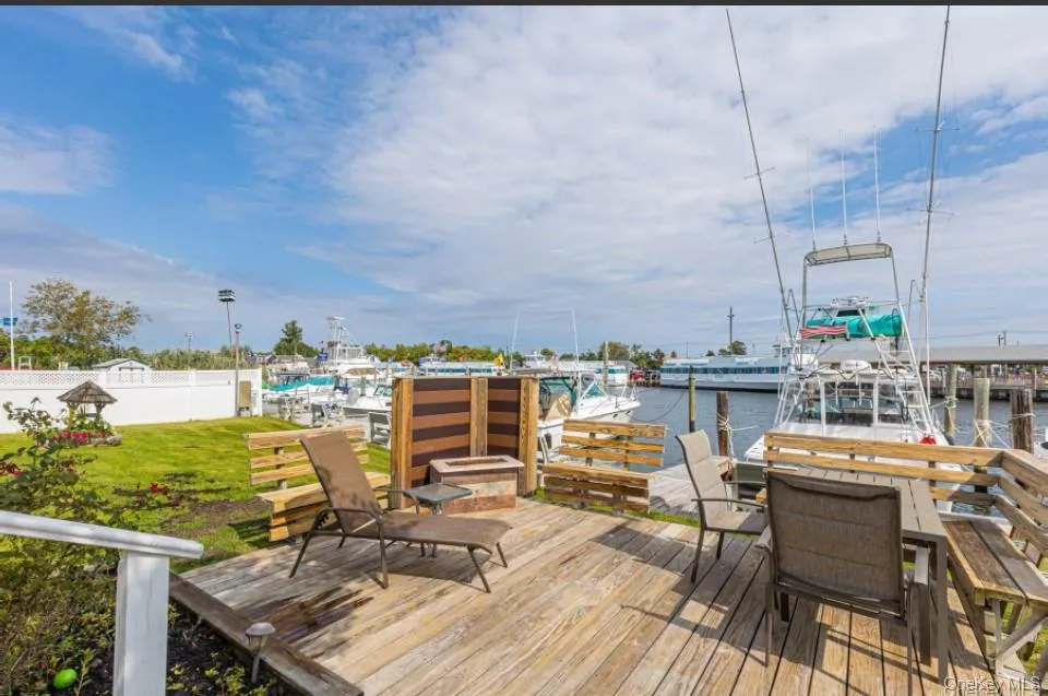 Wooden terrace featuring a water view, a boat dock, and a yard Wooden terrace featuring a water view, a boat dock, and a yard