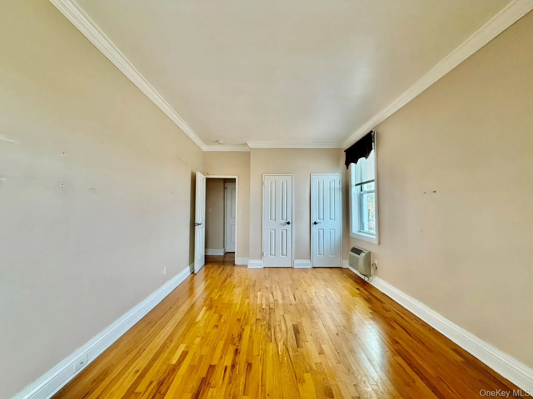 Unfurnished bedroom with multiple closets, ornamental molding, and hardwood / wood-style floors Unfurnished bedroom with multiple closets, ornamental molding, and hardwood / wood-style floors