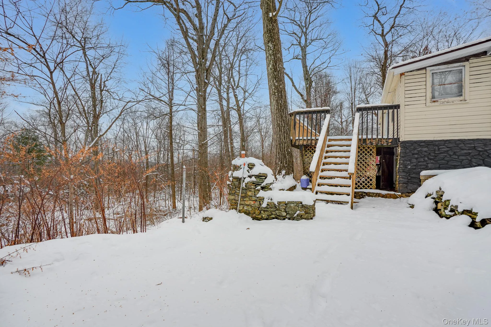 Yard layered in snow with a deck and stairway Yard layered in snow with a deck and stairway