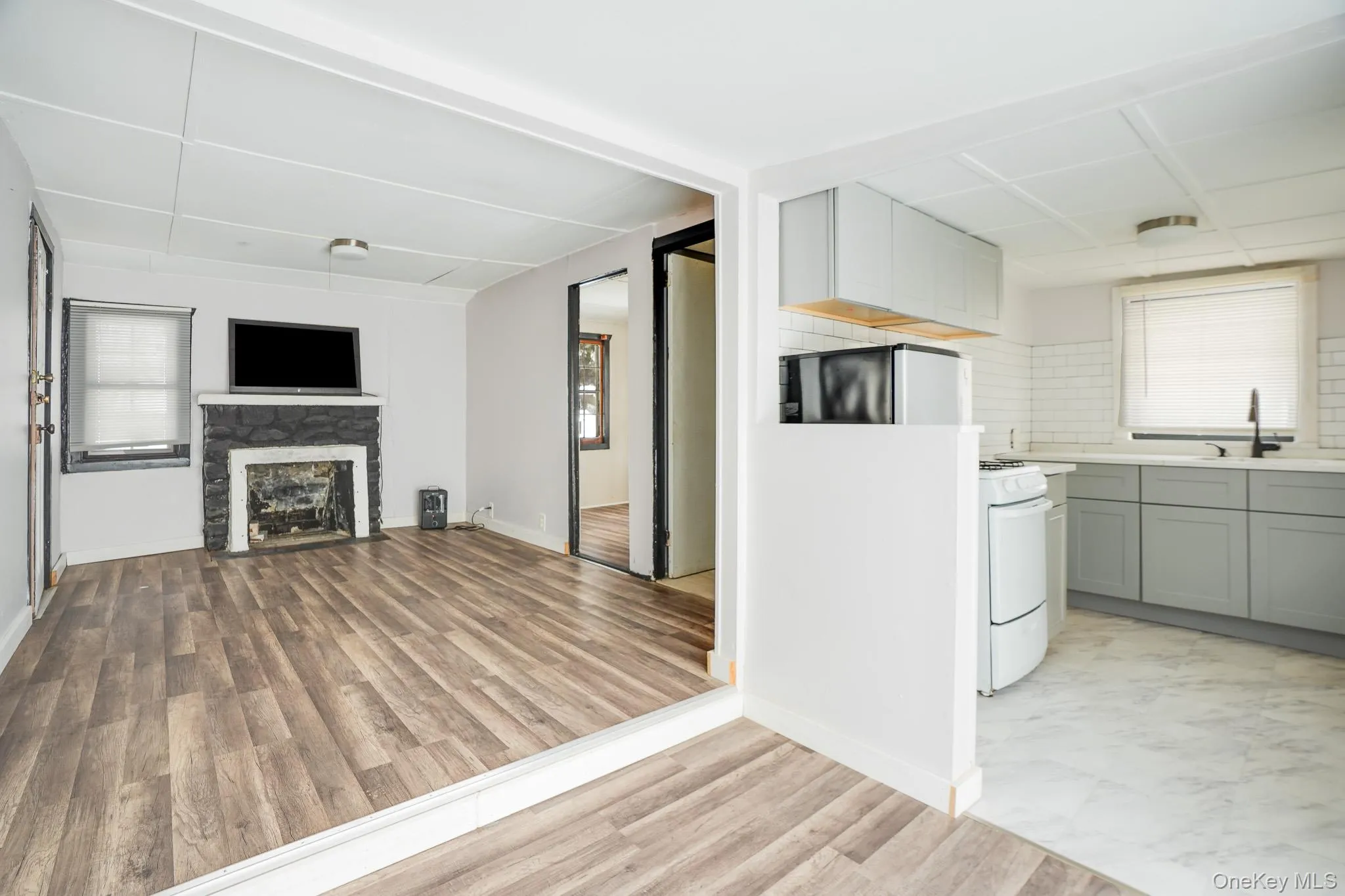 Kitchen with gray cabinets, open floor plan, white range with gas cooktop, and light wood-style floors Kitchen with gray cabinets, open floor plan, white range with gas cooktop, and light wood-style floors
