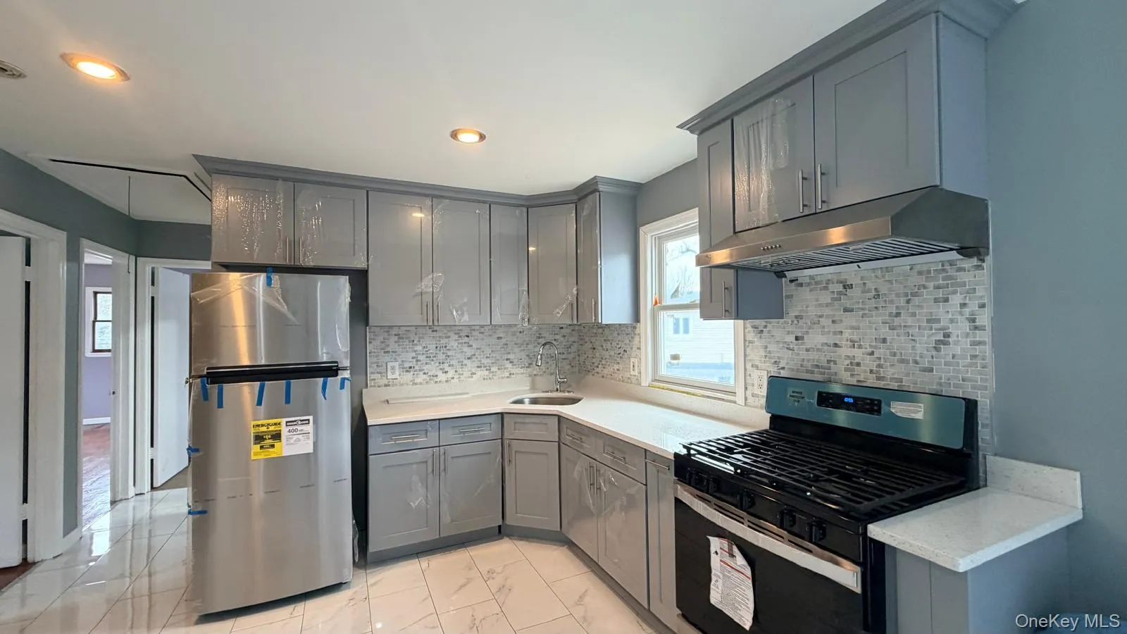 Kitchen with stainless steel appliances, gray cabinets, light marble finish flooring, under new cabinet range hood, and recessed lighting Kitchen with stainless steel appliances, gray cabinets, light marble finish flooring, under new cabinet range hood, and recessed lighting