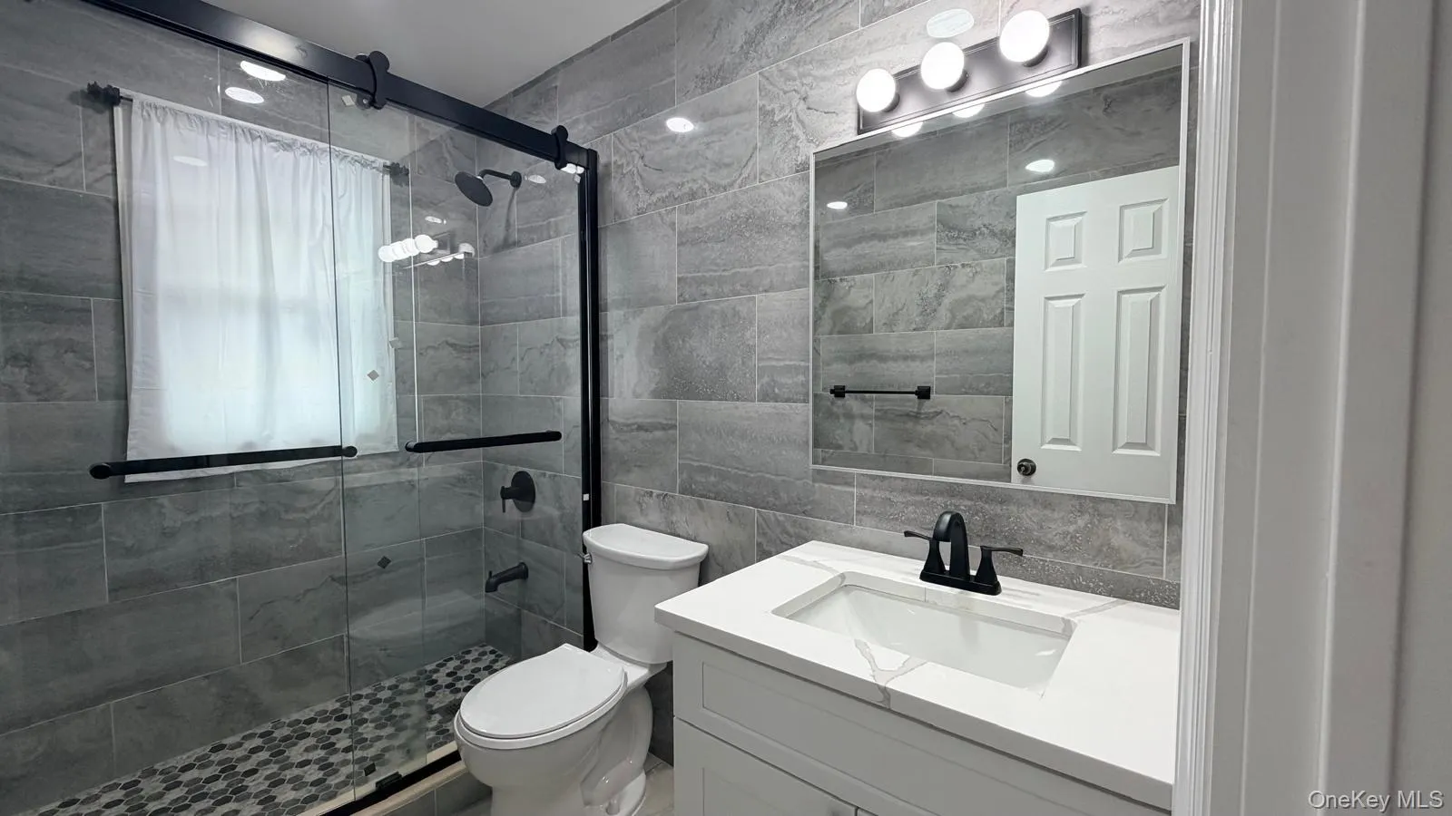 Bathroom featuring tile walls, vanity, and a shower stall Bathroom featuring tile walls, vanity, and a shower stall