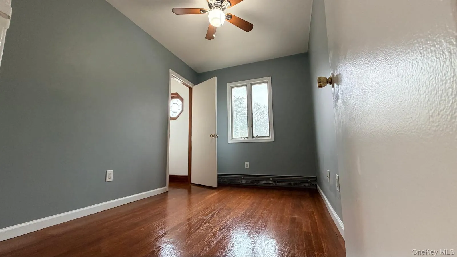 Empty room with dark wood-style floors and a ceiling fan Empty room with dark wood-style floors and a ceiling fan