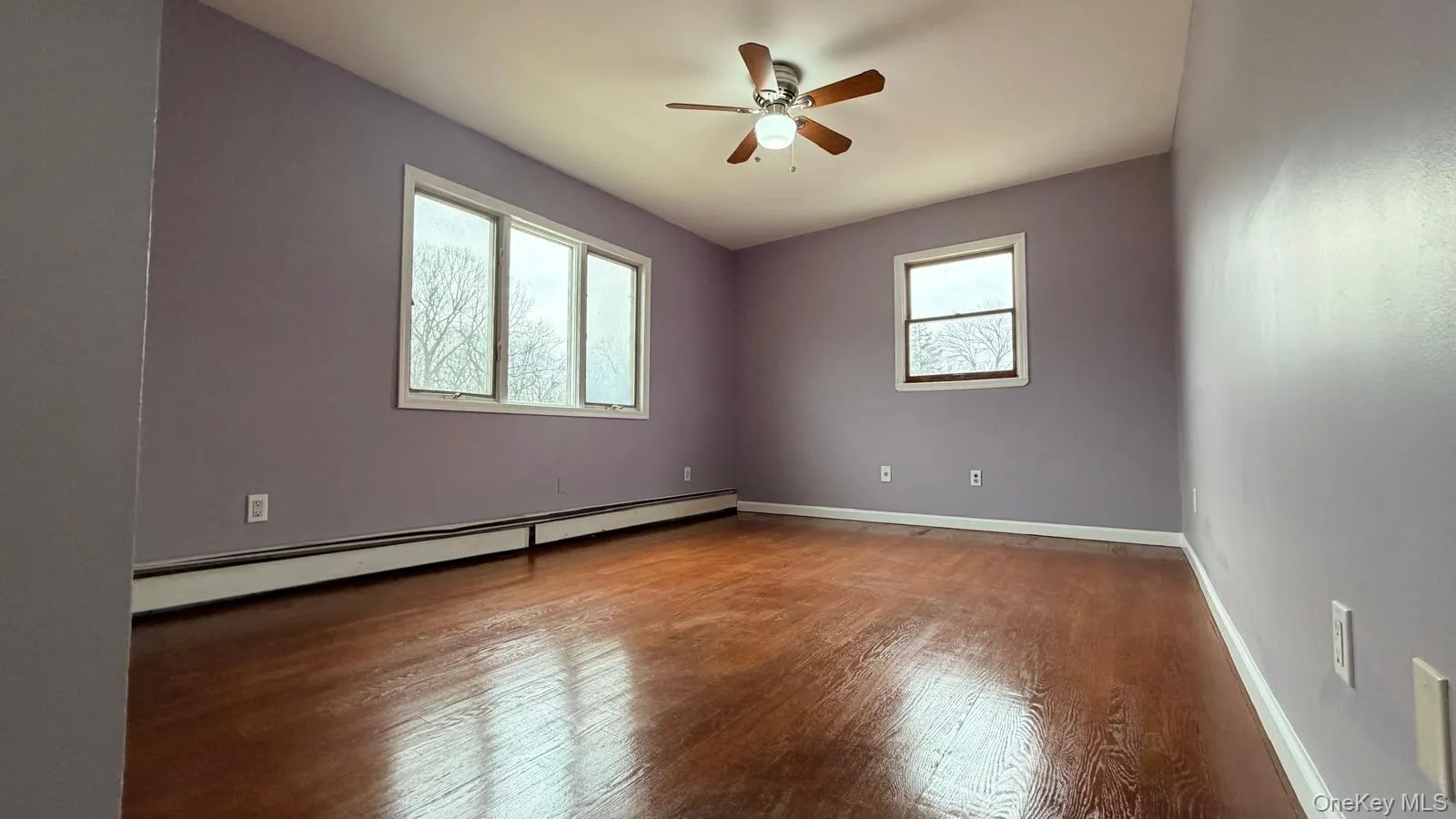 Unfurnished room with baseboard heating, hardwood / wood-style flooring, and a ceiling fan Unfurnished room with baseboard heating, hardwood / wood-style flooring, and a ceiling fan