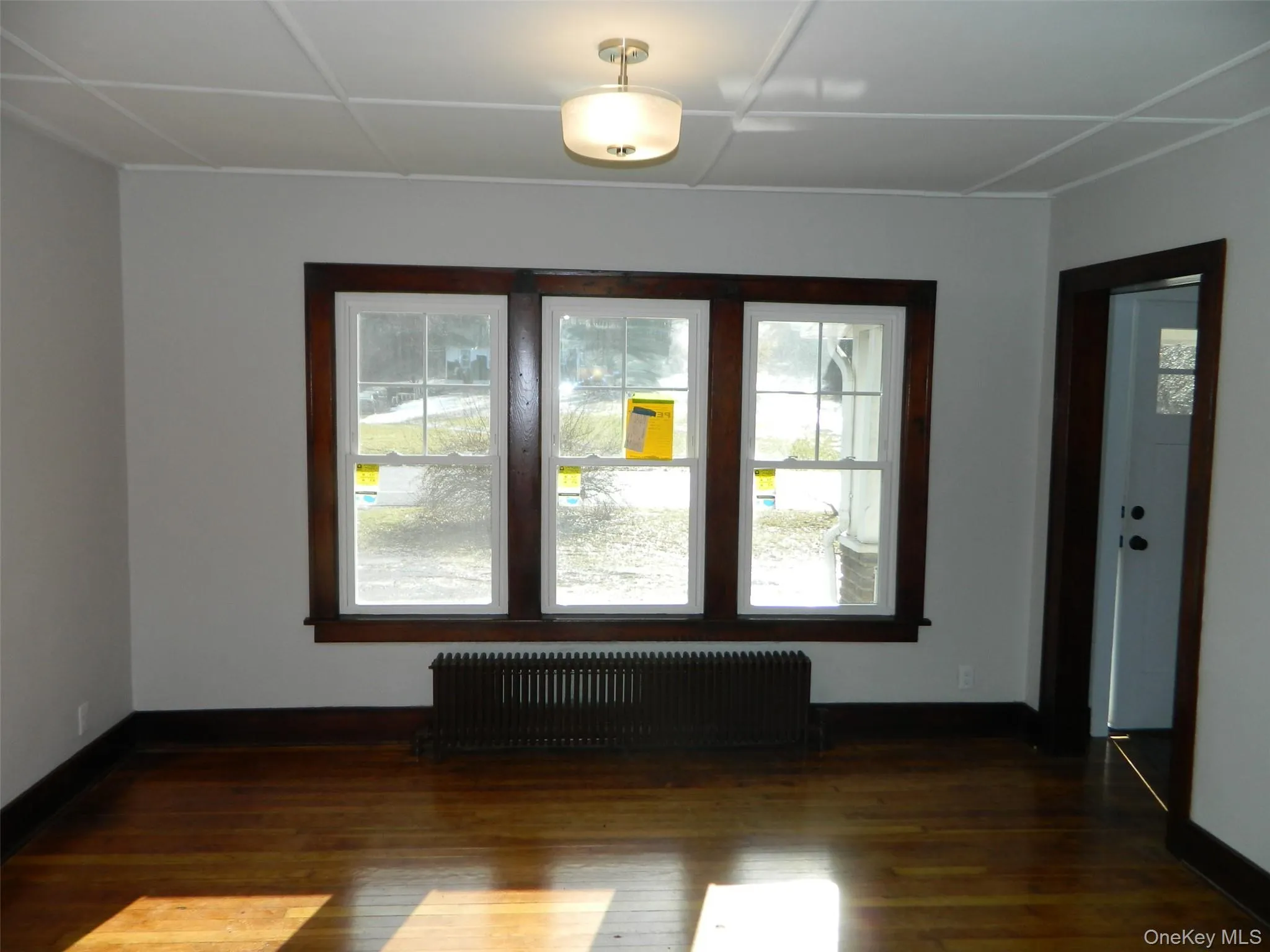 Spare room featuring radiator heating unit and dark wood-type flooring Spare room featuring radiator heating unit and dark wood-type flooring