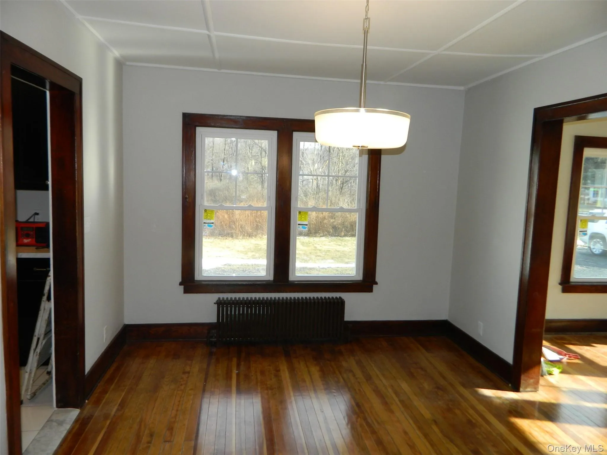 Unfurnished dining area featuring radiator heating unit and dark wood finished floors Unfurnished dining area featuring radiator heating unit and dark wood finished floors
