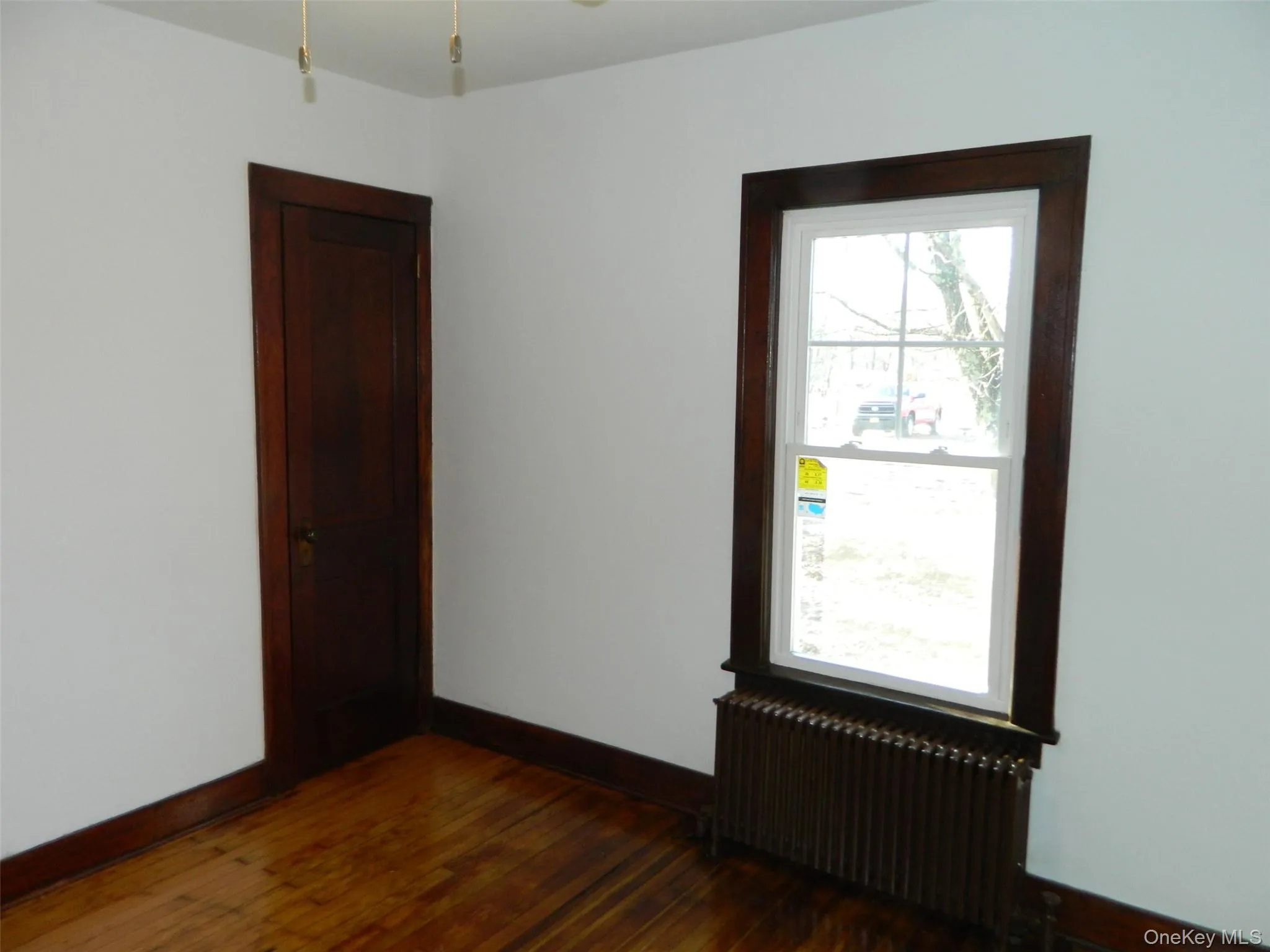 Spare room featuring radiator, dark wood-style floors, and a ceiling fan Spare room featuring radiator, dark wood-style floors, and a ceiling fan
