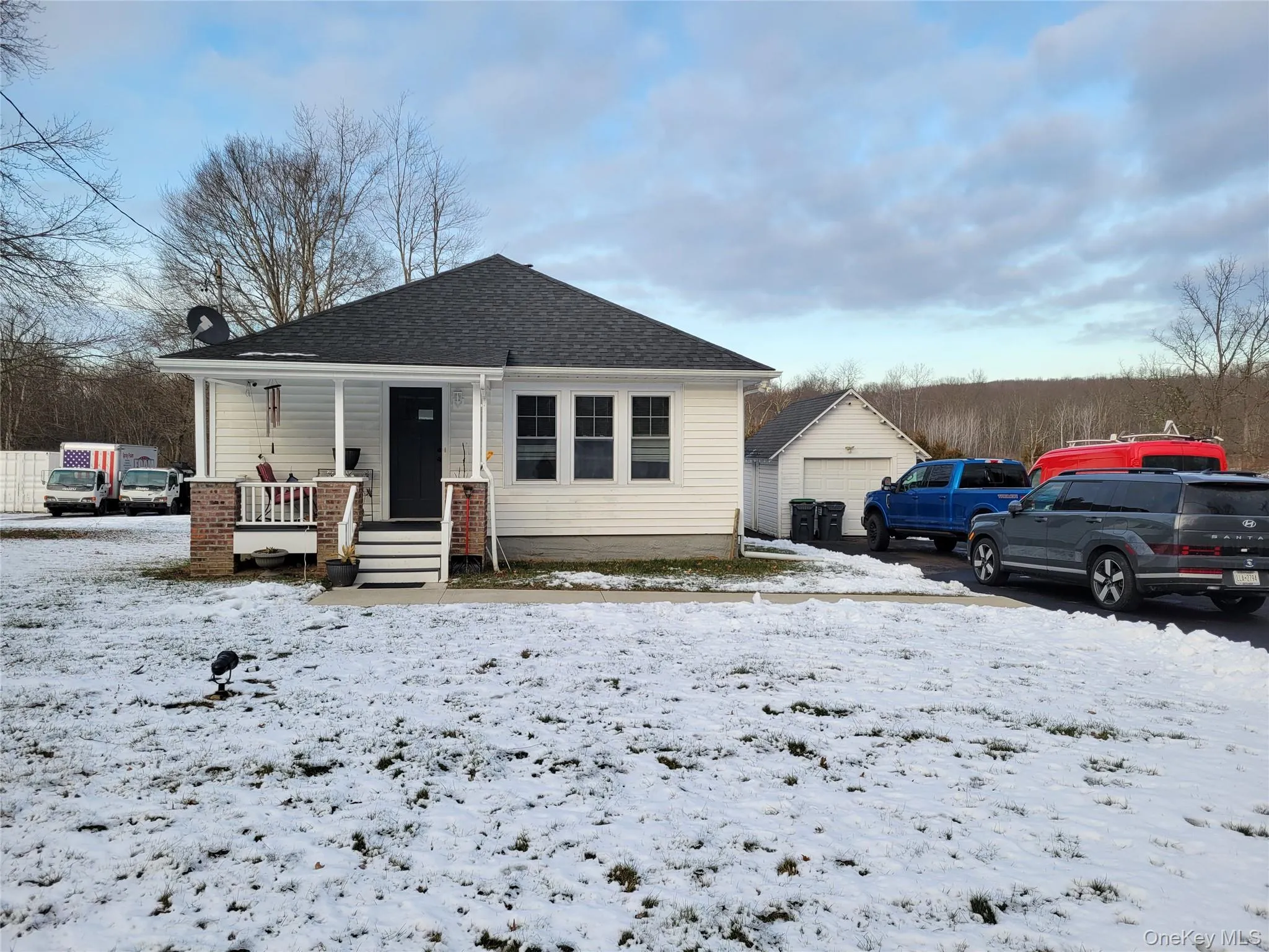 Bungalow-style home featuring covered porch, a shingled roof, an outbuilding, and a garage Bungalow-style home featuring covered porch, a shingled roof, an outbuilding, and a garage