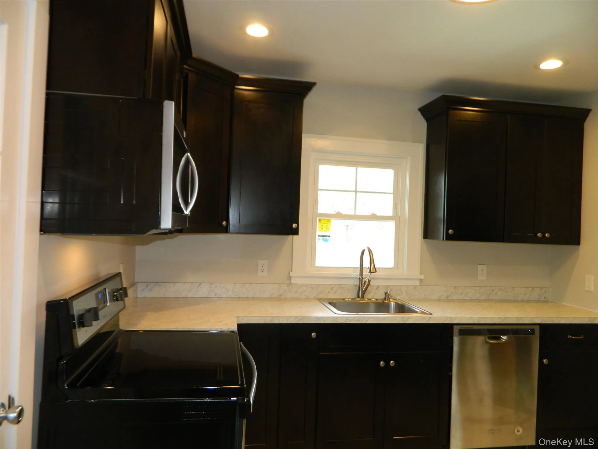 Kitchen featuring stainless steel appliances, light countertops, dark cabinets, and recessed lighting Kitchen featuring stainless steel appliances, light countertops, dark cabinets, and recessed lighting