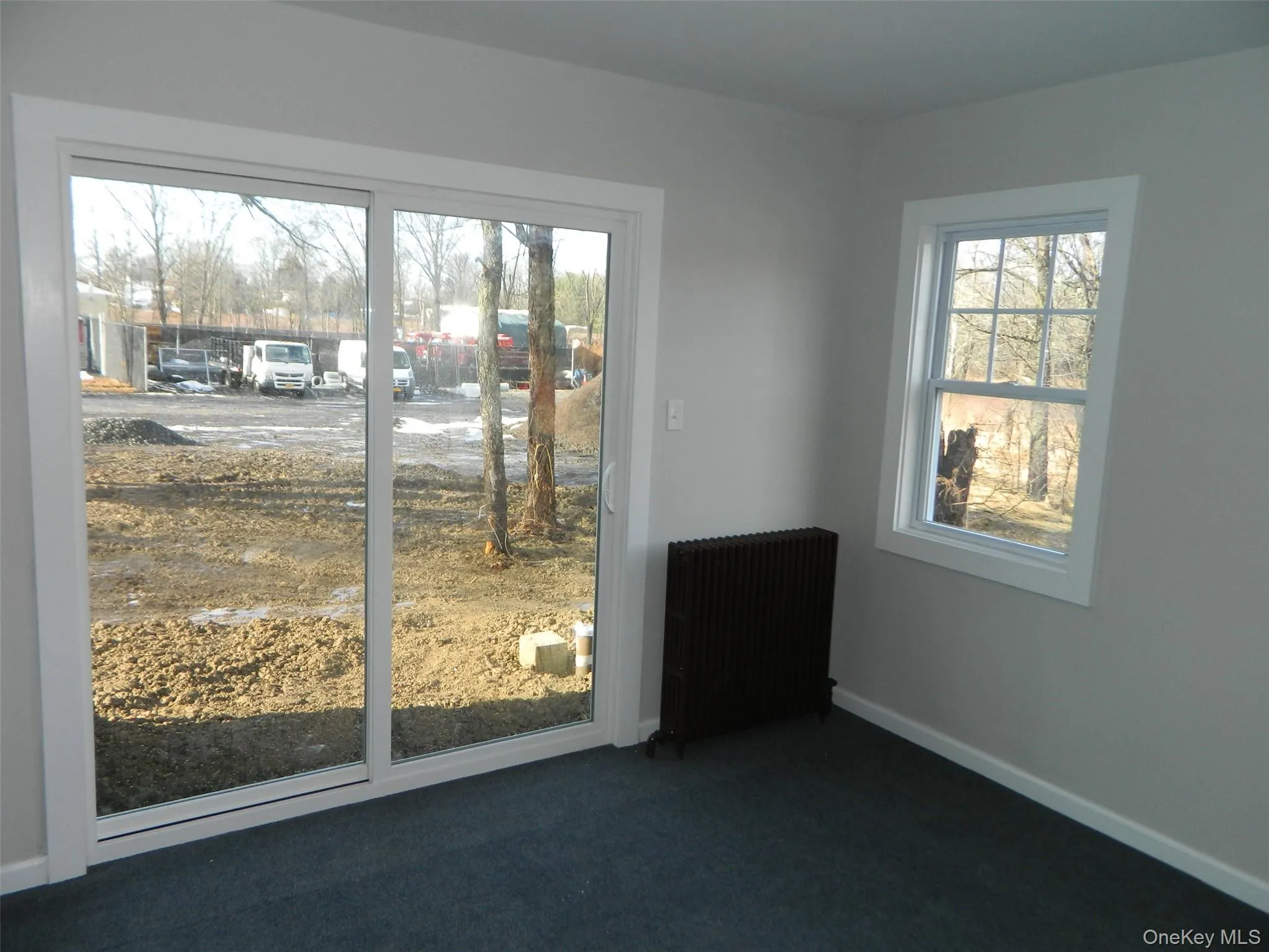 Unfurnished room with radiator and dark carpet Unfurnished room with radiator and dark carpet