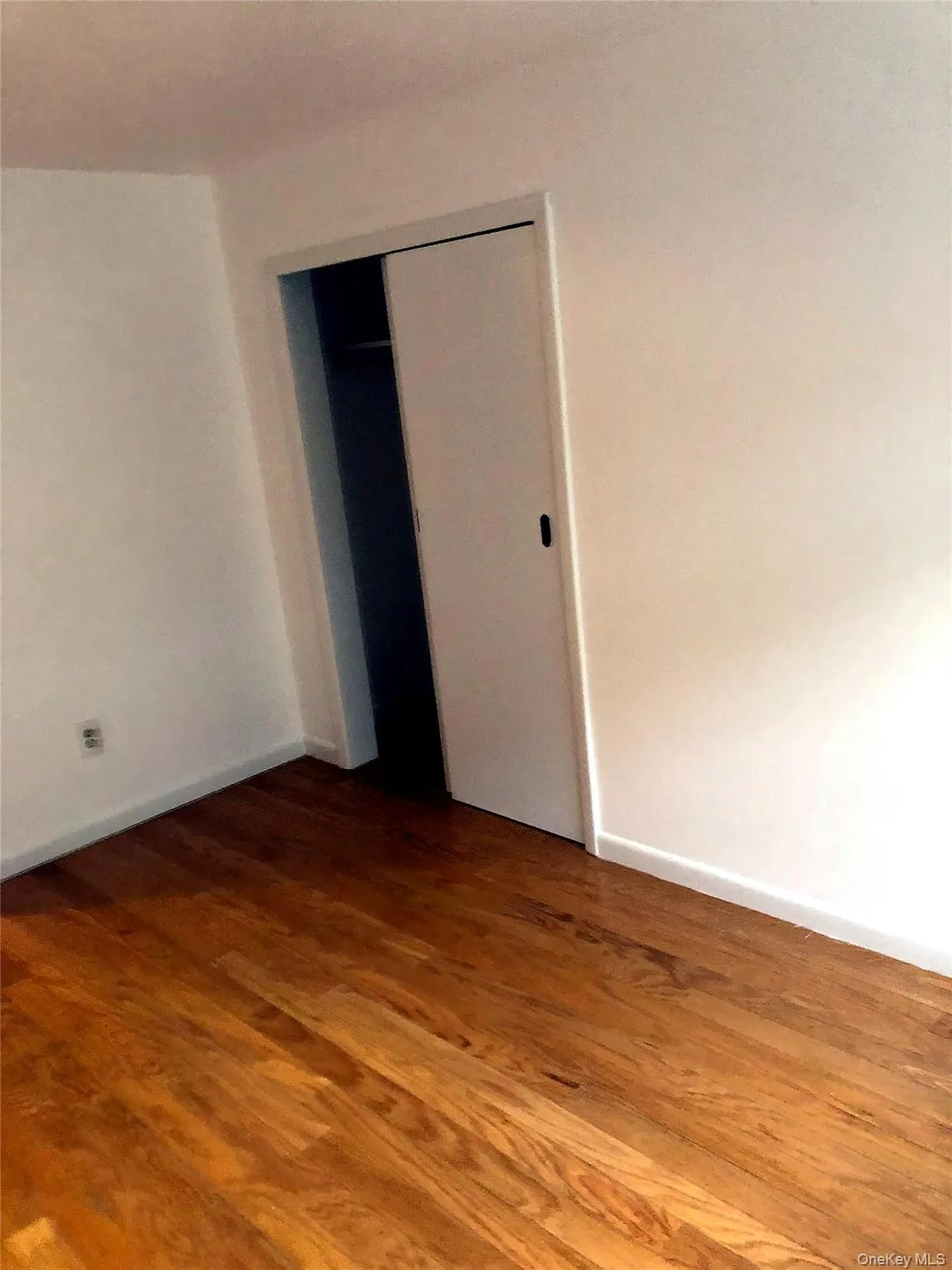 Unfurnished bedroom with dark wood-style flooring and a closet Unfurnished bedroom with dark wood-style flooring and a closet