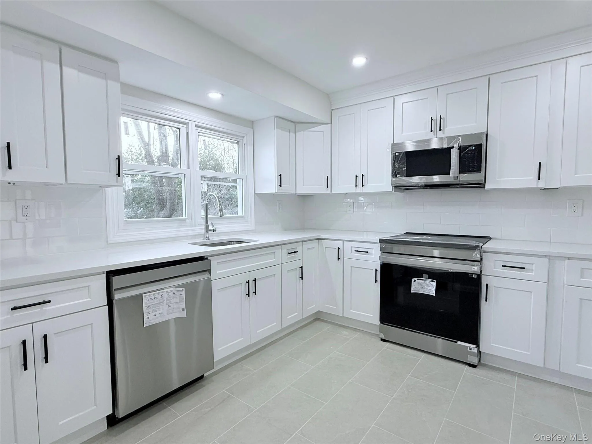 Kitchen featuring stainless steel appliances, white cabinets, backsplash, light stone countertops, and recessed lighting Kitchen featuring stainless steel appliances, white cabinets, backsplash, light stone countertops, and recessed lighting