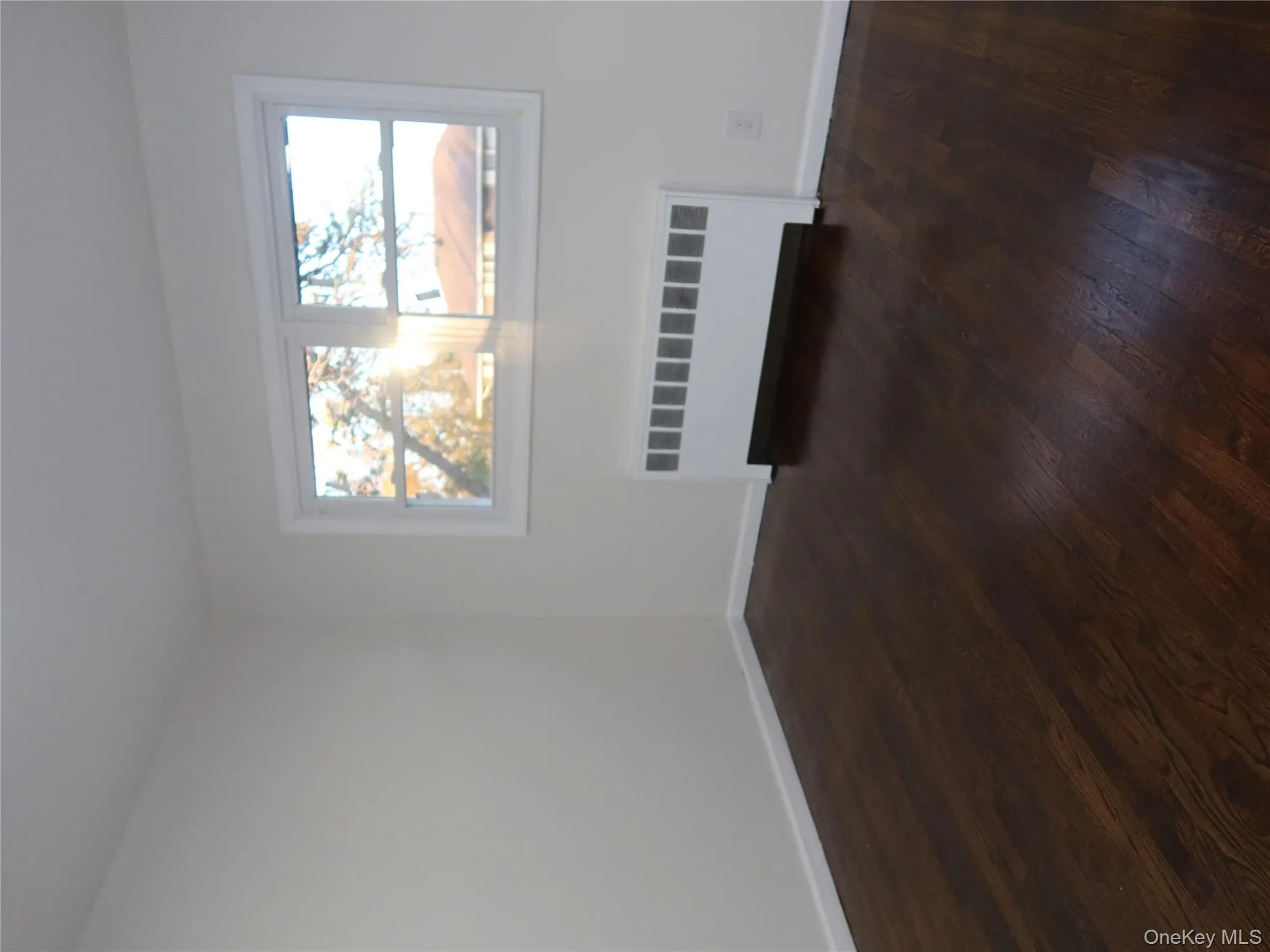 Empty room featuring radiator heating unit and dark wood finished floors Empty room featuring radiator heating unit and dark wood finished floors