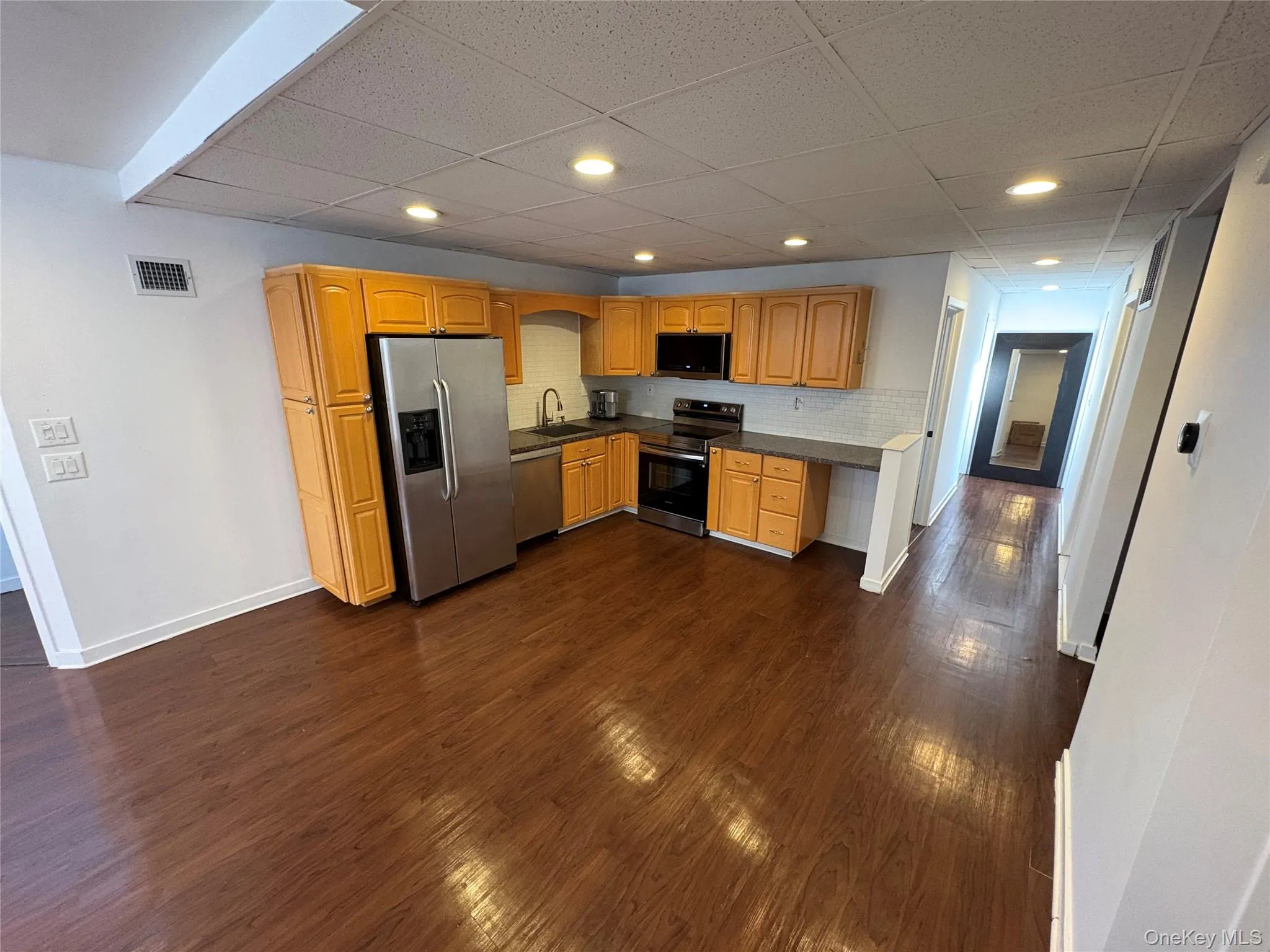 Kitchen with stainless steel appliances, tasteful backsplash, dark countertops, recessed lighting, and a drop ceiling Kitchen with stainless steel appliances, tasteful backsplash, dark countertops, recessed lighting, and a drop ceiling