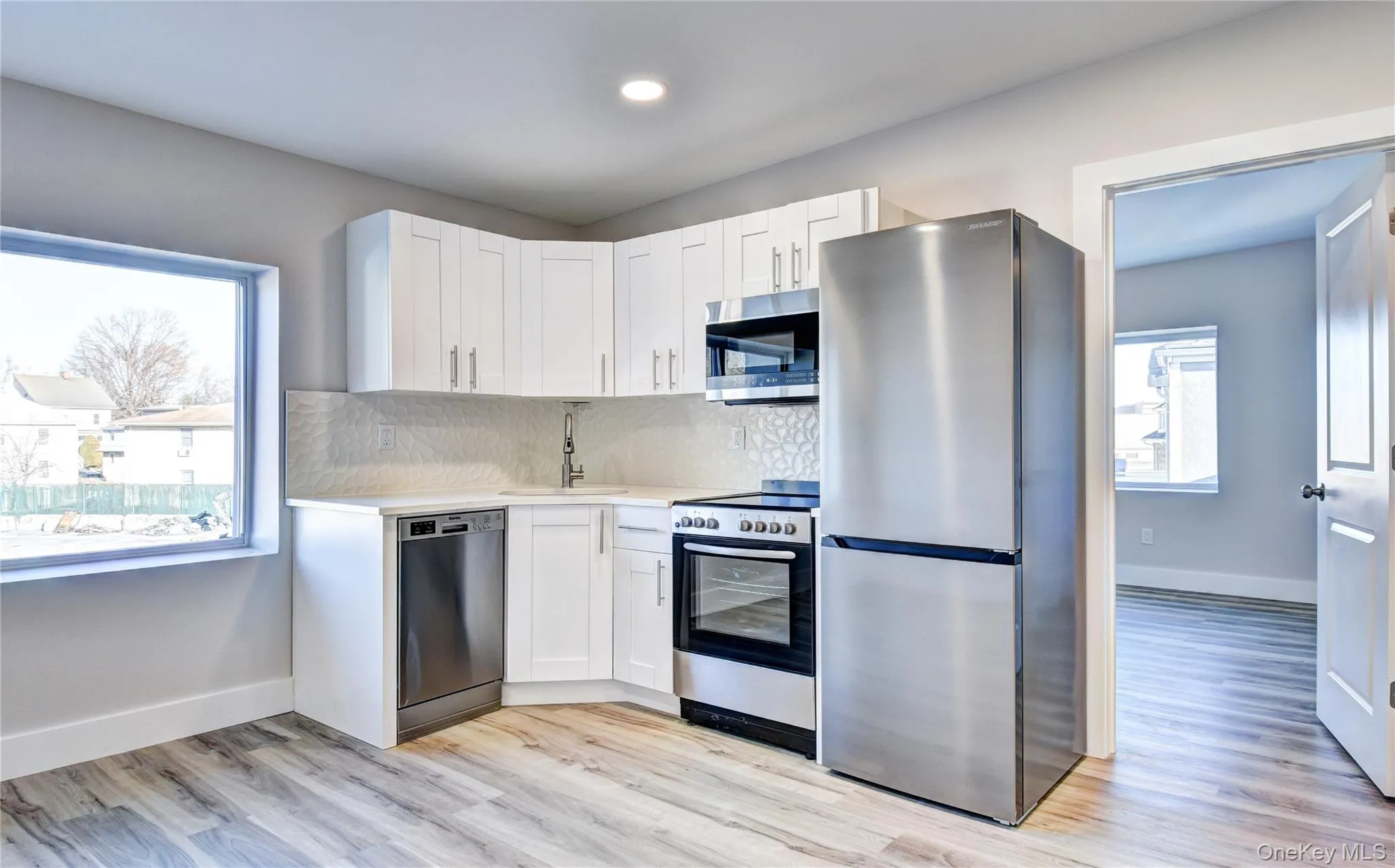 Kitchen with stainless steel appliances, white cabinetry, backsplash, light wood-style flooring, and recessed lighting Kitchen with stainless steel appliances, white cabinetry, backsplash, light wood-style flooring, and recessed lighting