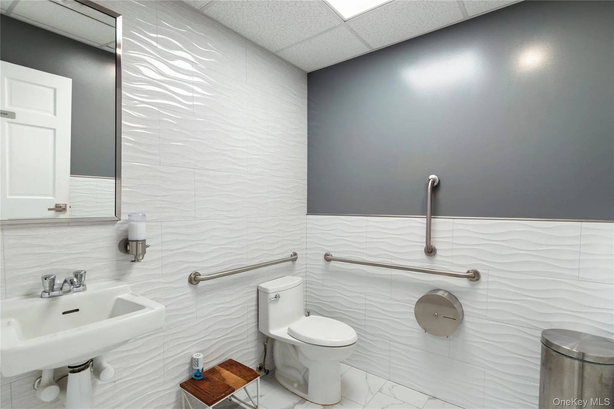 Bathroom featuring a paneled ceiling, tile walls, and marble finish flooring Bathroom featuring a paneled ceiling, tile walls, and marble finish flooring