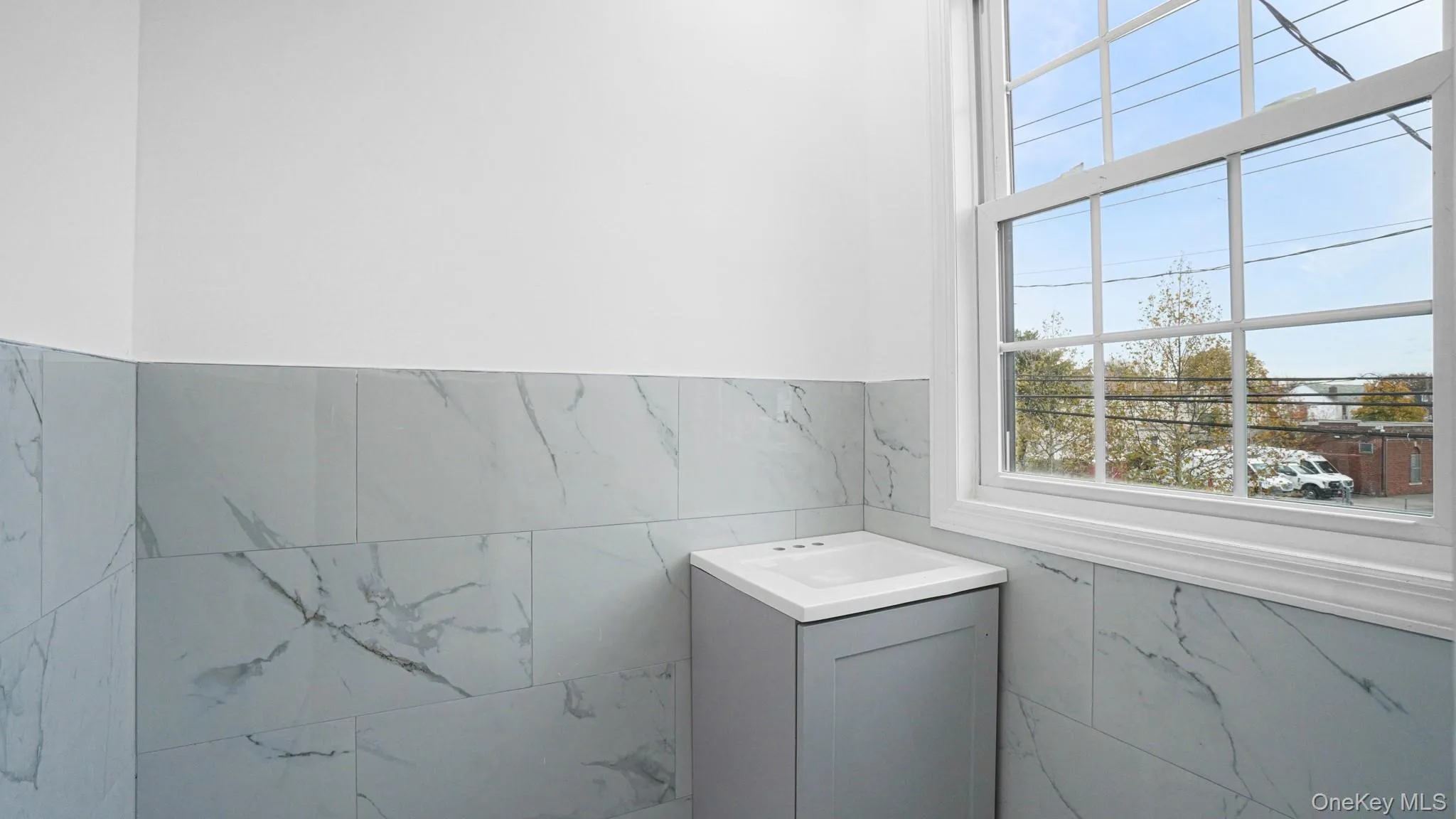 Half bathroom featuring a wainscoted wall, tile walls, and vanity Half bathroom featuring a wainscoted wall, tile walls, and vanity