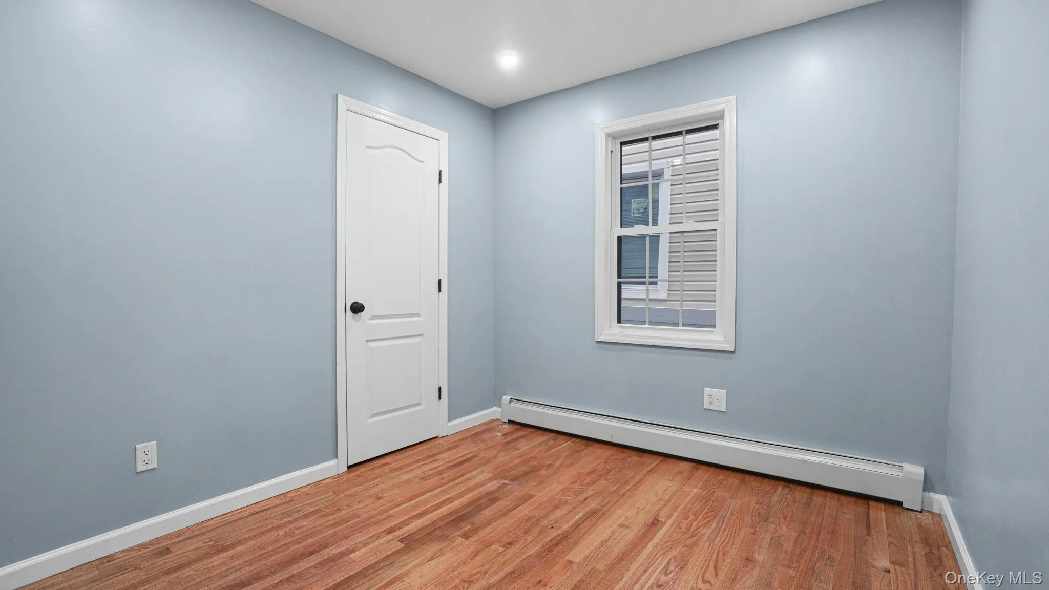 Unfurnished room with a baseboard radiator and light wood-style floors Unfurnished room with a baseboard radiator and light wood-style floors