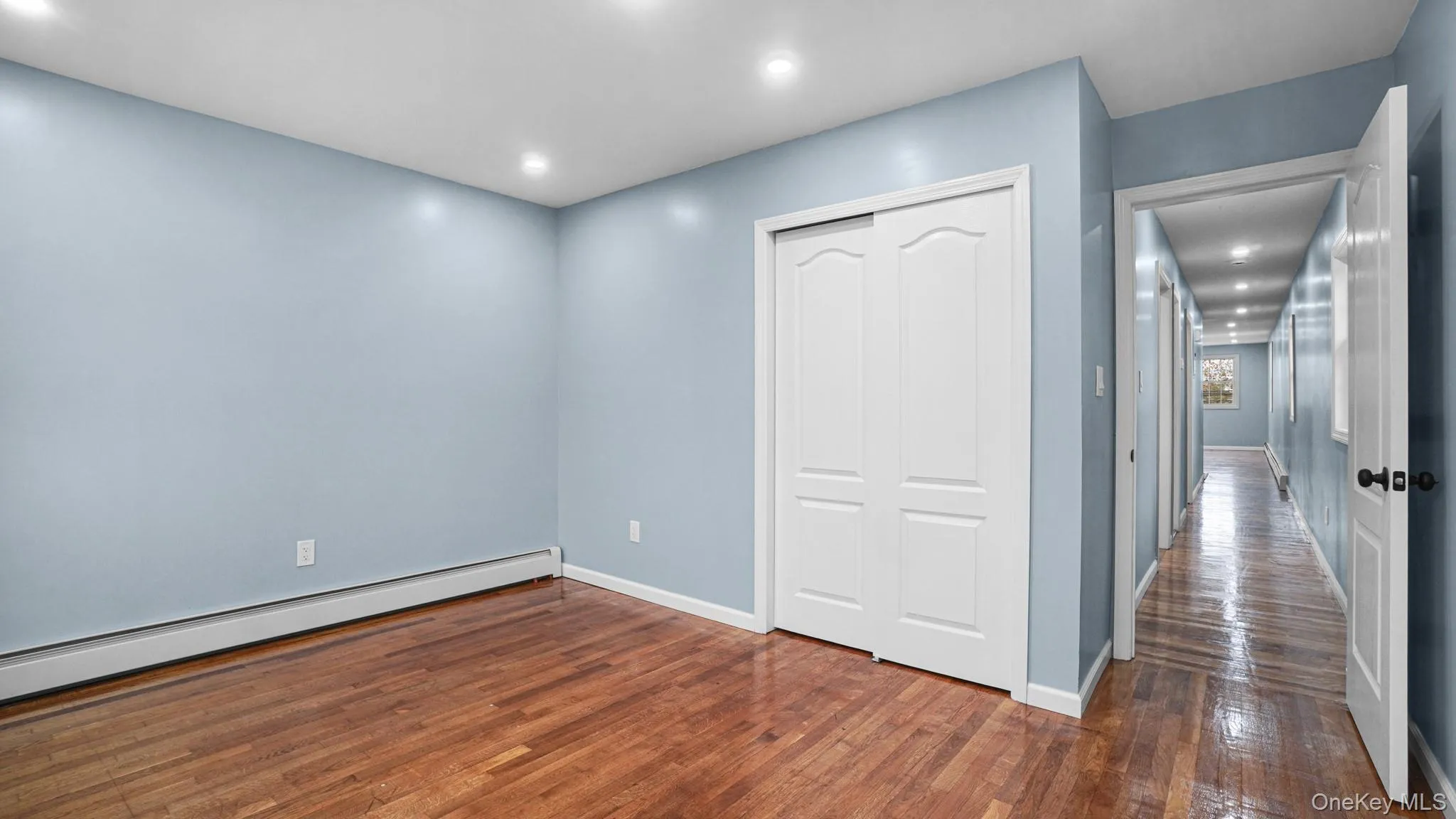 Unfurnished bedroom with a closet, dark wood finished floors, a baseboard radiator, and recessed lighting Unfurnished bedroom with a closet, dark wood finished floors, a baseboard radiator, and recessed lighting