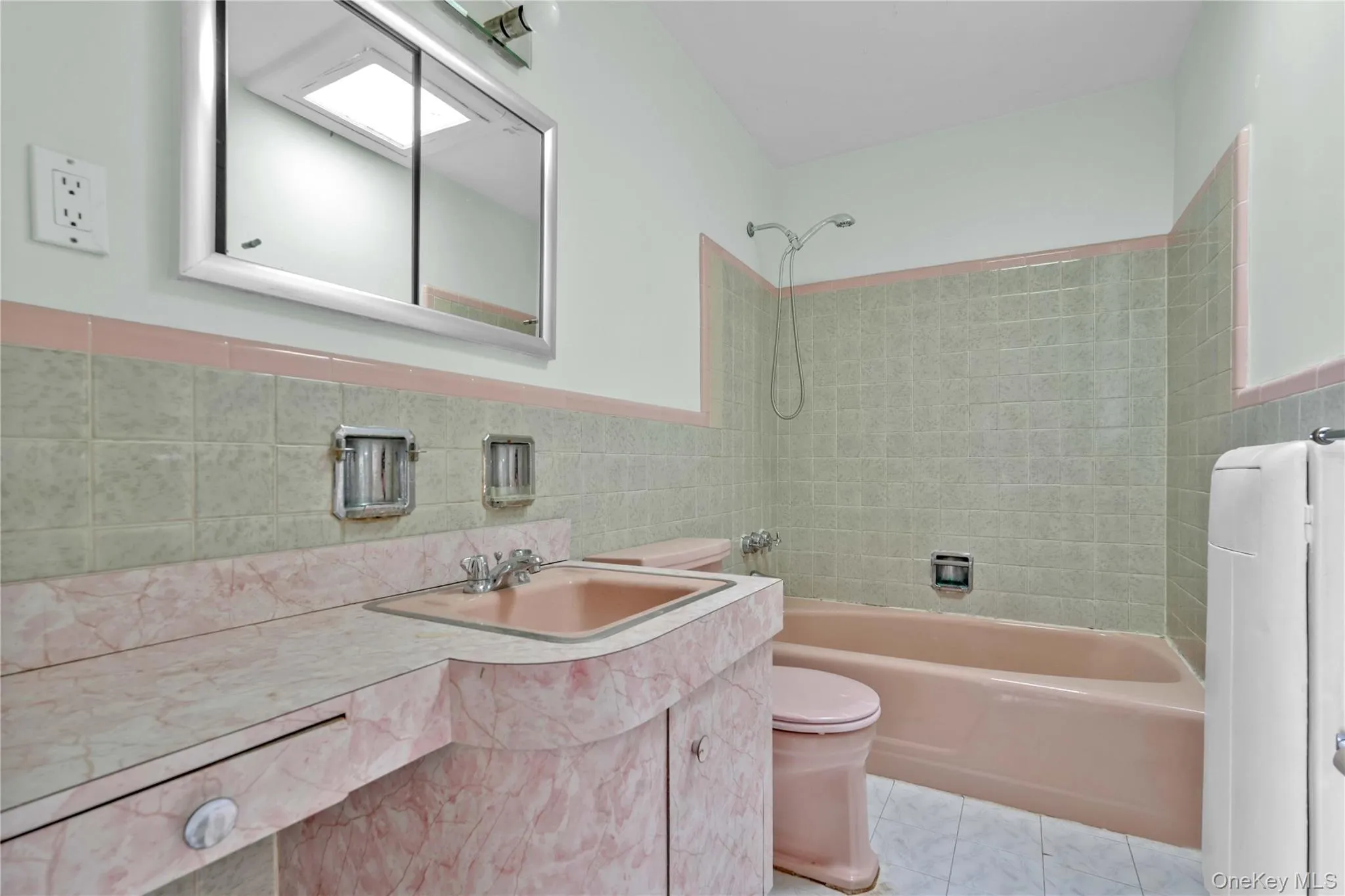 Full bathroom with vanity, tile walls, shower / tub combination, wainscoting, and light tile patterned floors Full bathroom with vanity, tile walls, shower / tub combination, wainscoting, and light tile patterned floors