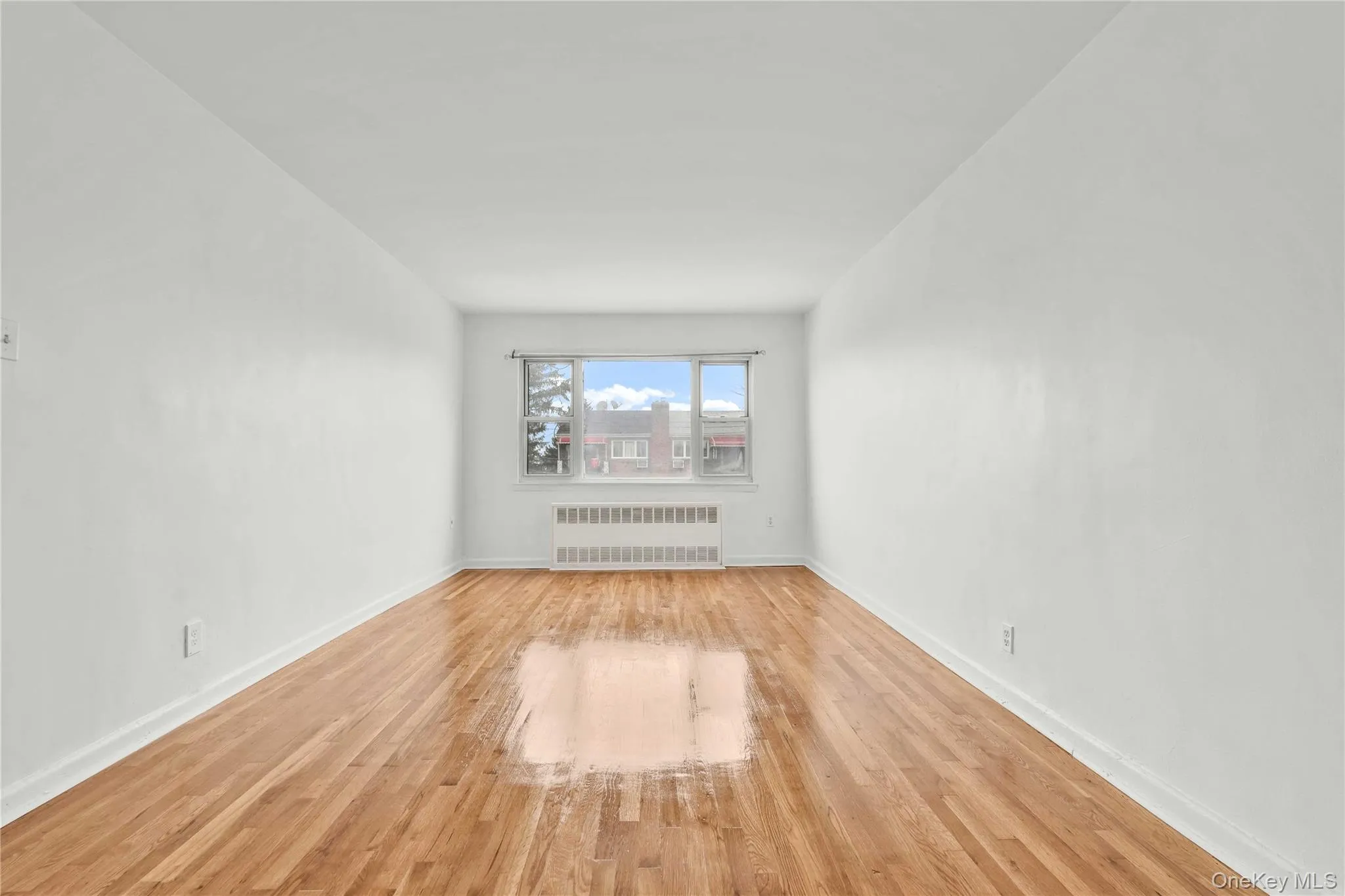 Empty room featuring radiator heating unit and wood finished floors Empty room featuring radiator heating unit and wood finished floors