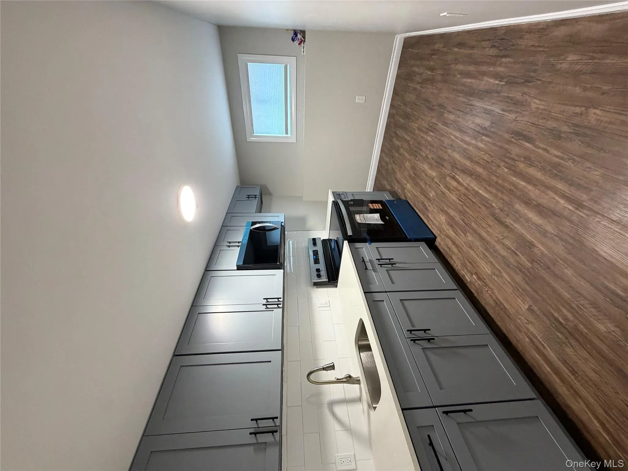 Kitchen featuring gray cabinets, stove, backsplash, light stone countertops, and dark wood-type flooring Kitchen featuring gray cabinets, stove, backsplash, light stone countertops, and dark wood-type flooring