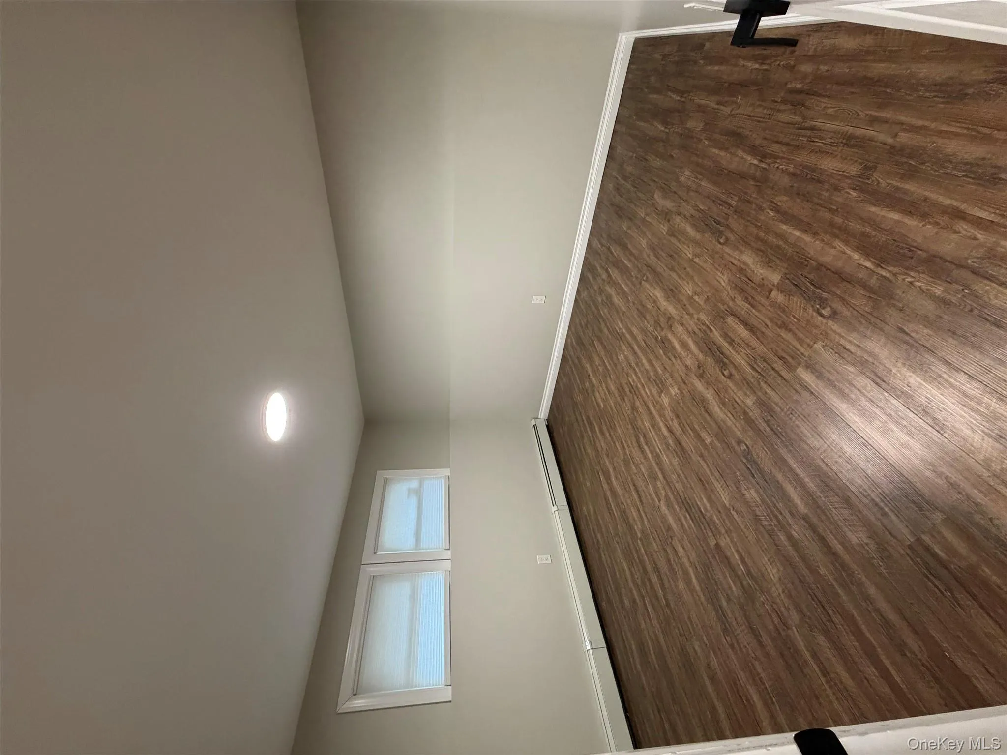 Empty room with dark wood-style flooring and a baseboard heating unit Empty room with dark wood-style flooring and a baseboard heating unit