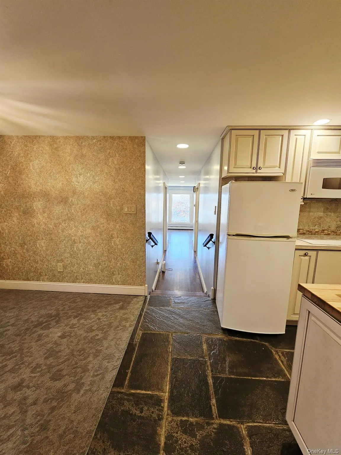 Hallway with stone tile flooring and dark colored carpet Hallway with stone tile flooring and dark colored carpet