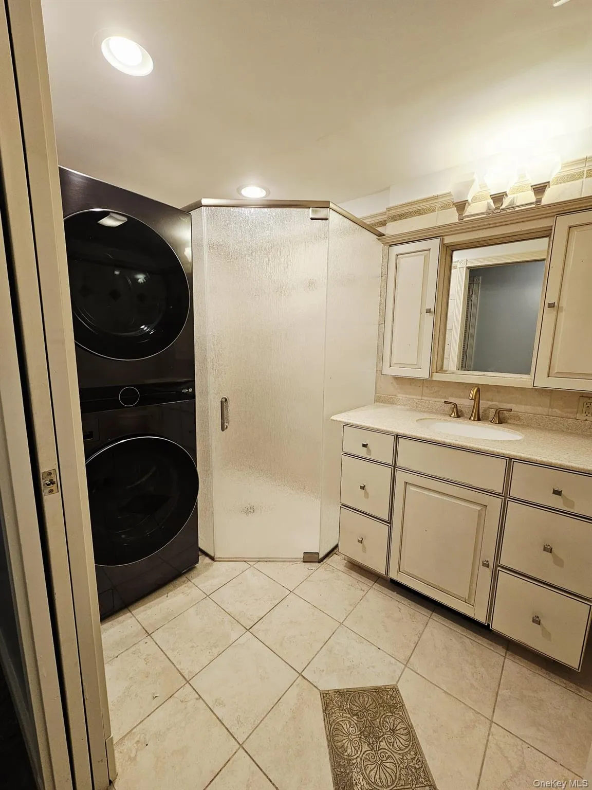Full bathroom featuring vanity, light tile patterned flooring, a shower stall, stacked washer / dryer, and recessed lighting Full bathroom featuring vanity, light tile patterned flooring, a shower stall, stacked washer / dryer, and recessed lighting