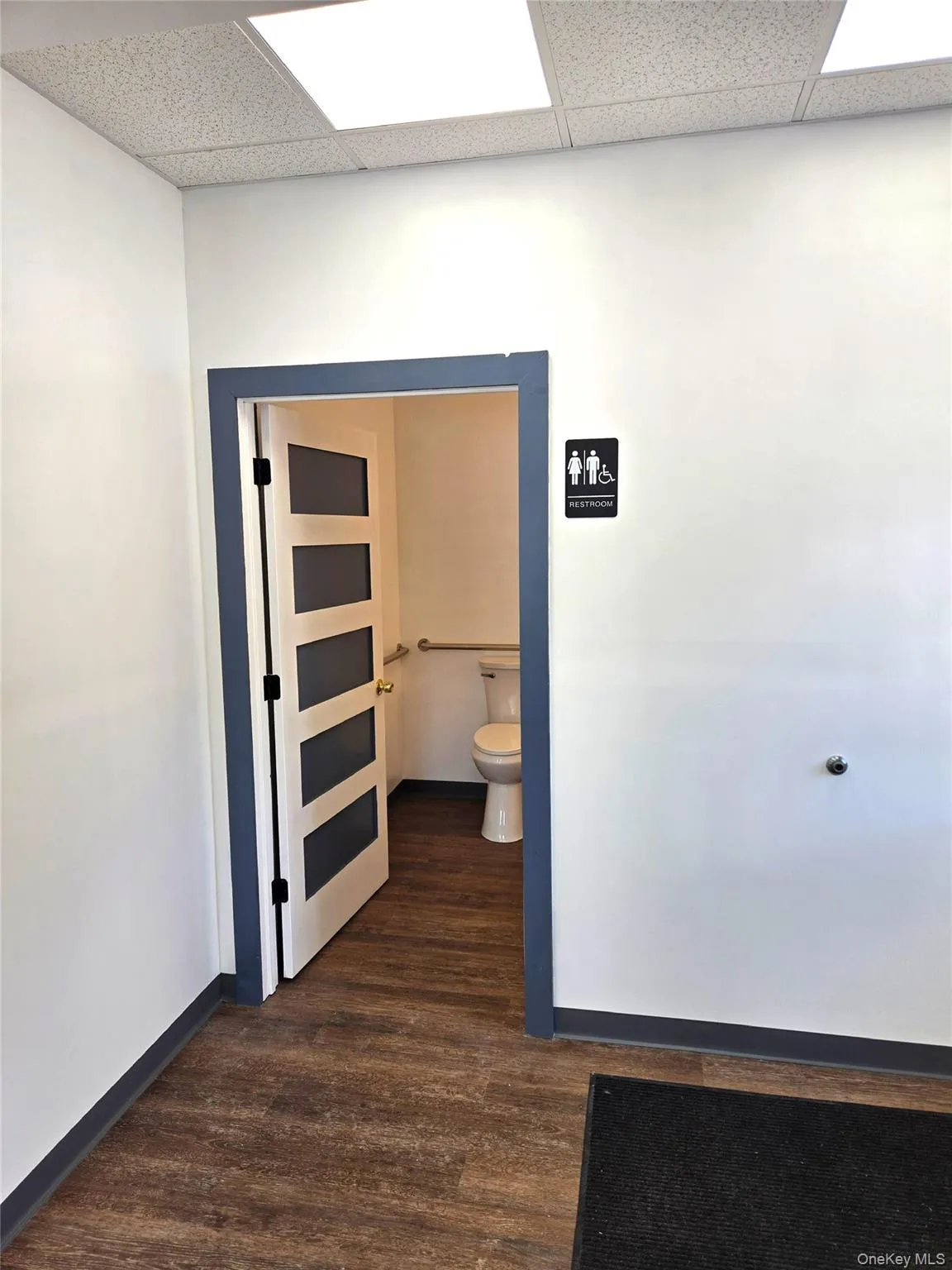 Hallway with dark wood-type flooring and a drop ceiling Hallway with dark wood-type flooring and a drop ceiling