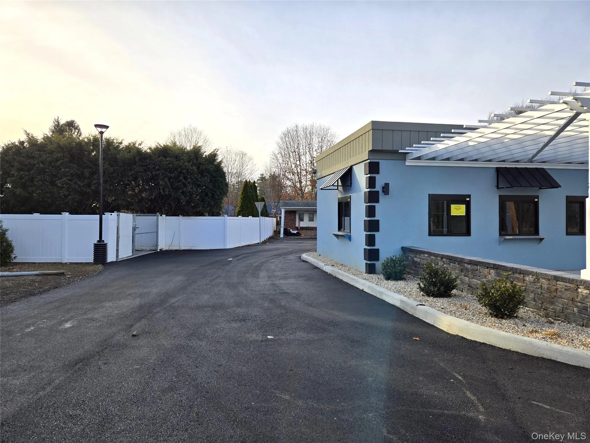 Property exterior at dusk featuring stucco siding, a gate, and a metal roof Property exterior at dusk featuring stucco siding, a gate, and a metal roof