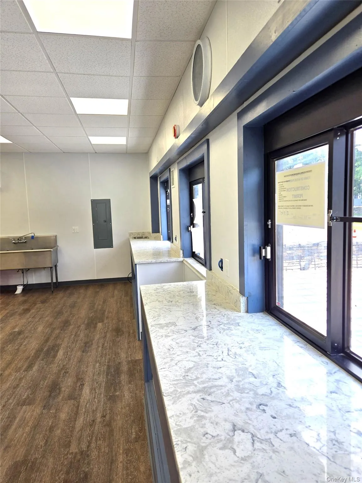 Kitchen with a paneled ceiling, light stone countertops, and electric panel Kitchen with a paneled ceiling, light stone countertops, and electric panel