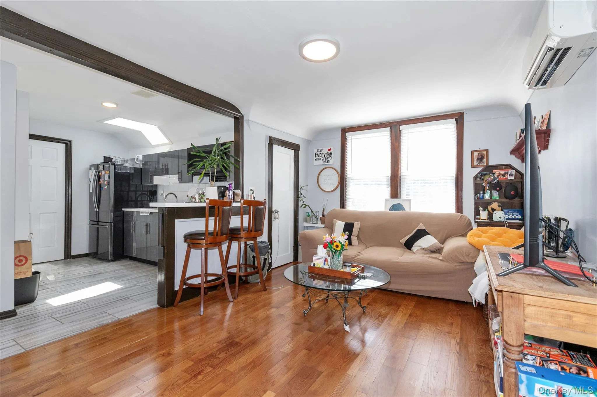 Living room with light wood-type flooring, an AC wall unit, and lofted ceiling Living room with light wood-type flooring, an AC wall unit, and lofted ceiling
