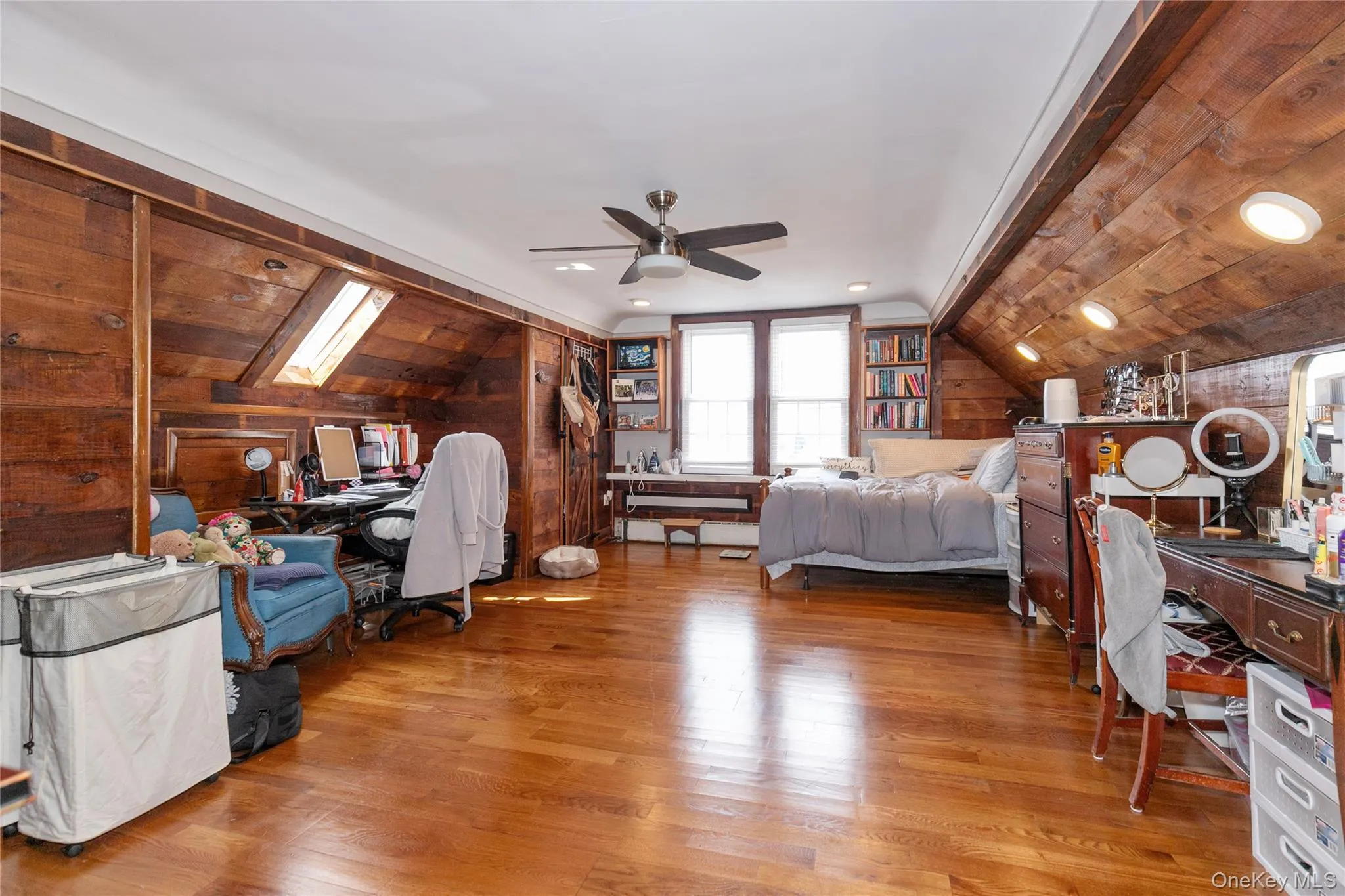 Bedroom featuring a desk, vaulted ceiling, wood walls, light wood-style floors, and a ceiling fan Bedroom featuring a desk, vaulted ceiling, wood walls, light wood-style floors, and a ceiling fan