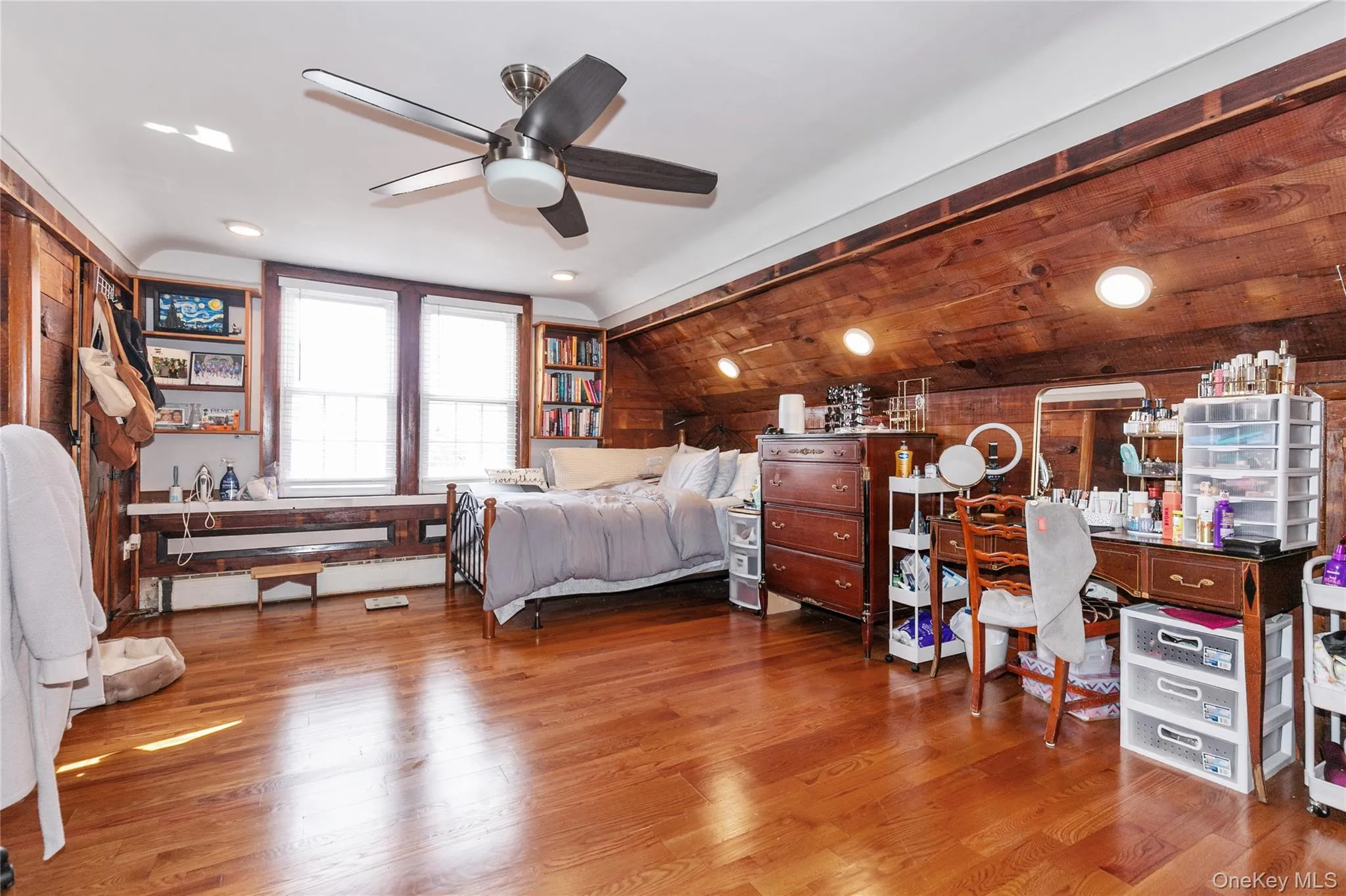 Bedroom featuring lofted ceiling, light wood-type flooring, ceiling fan, and wooden walls Bedroom featuring lofted ceiling, light wood-type flooring, ceiling fan, and wooden walls