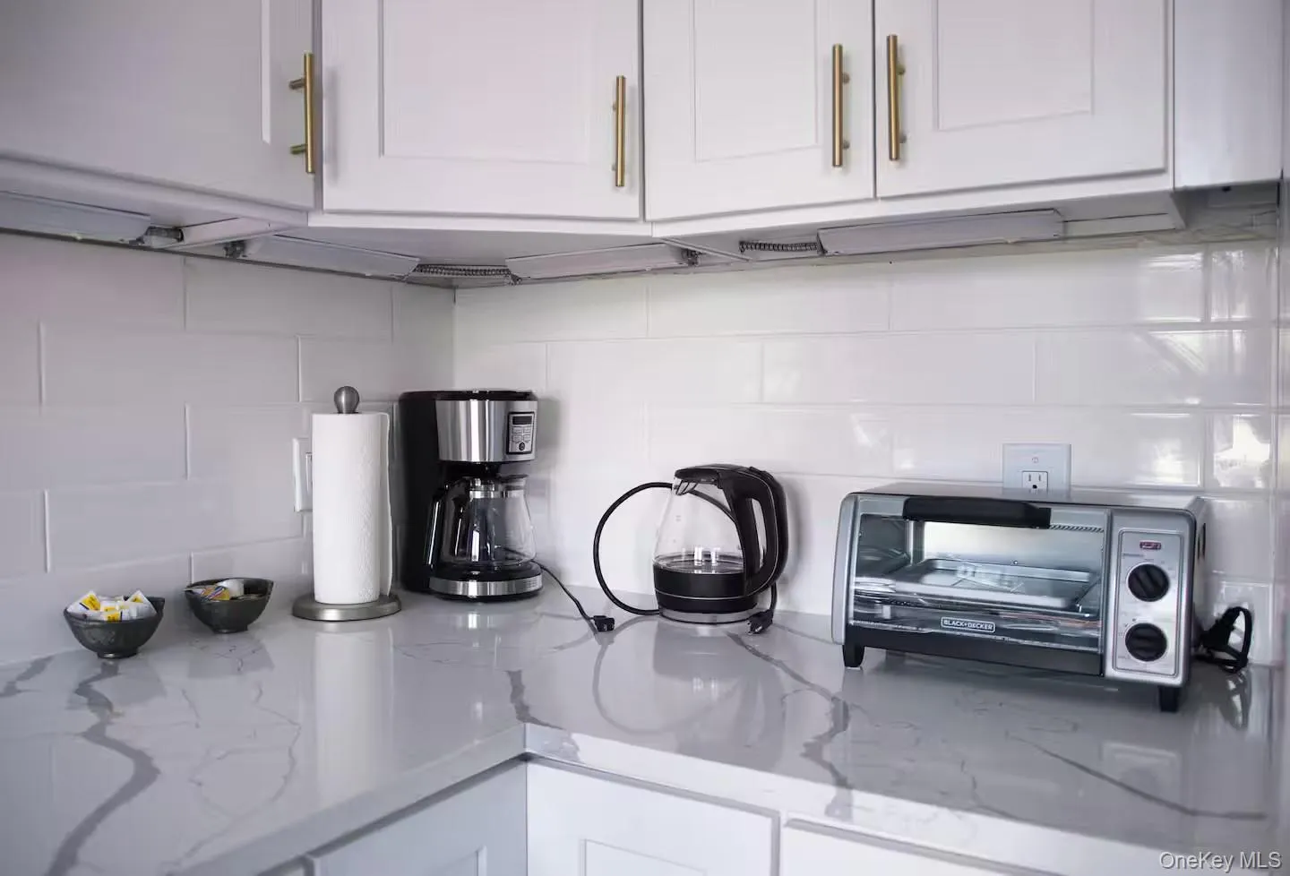 Kitchen view of white cabinetry, light stone counters, and decorative backsplash Kitchen view of white cabinetry, light stone counters, and decorative backsplash